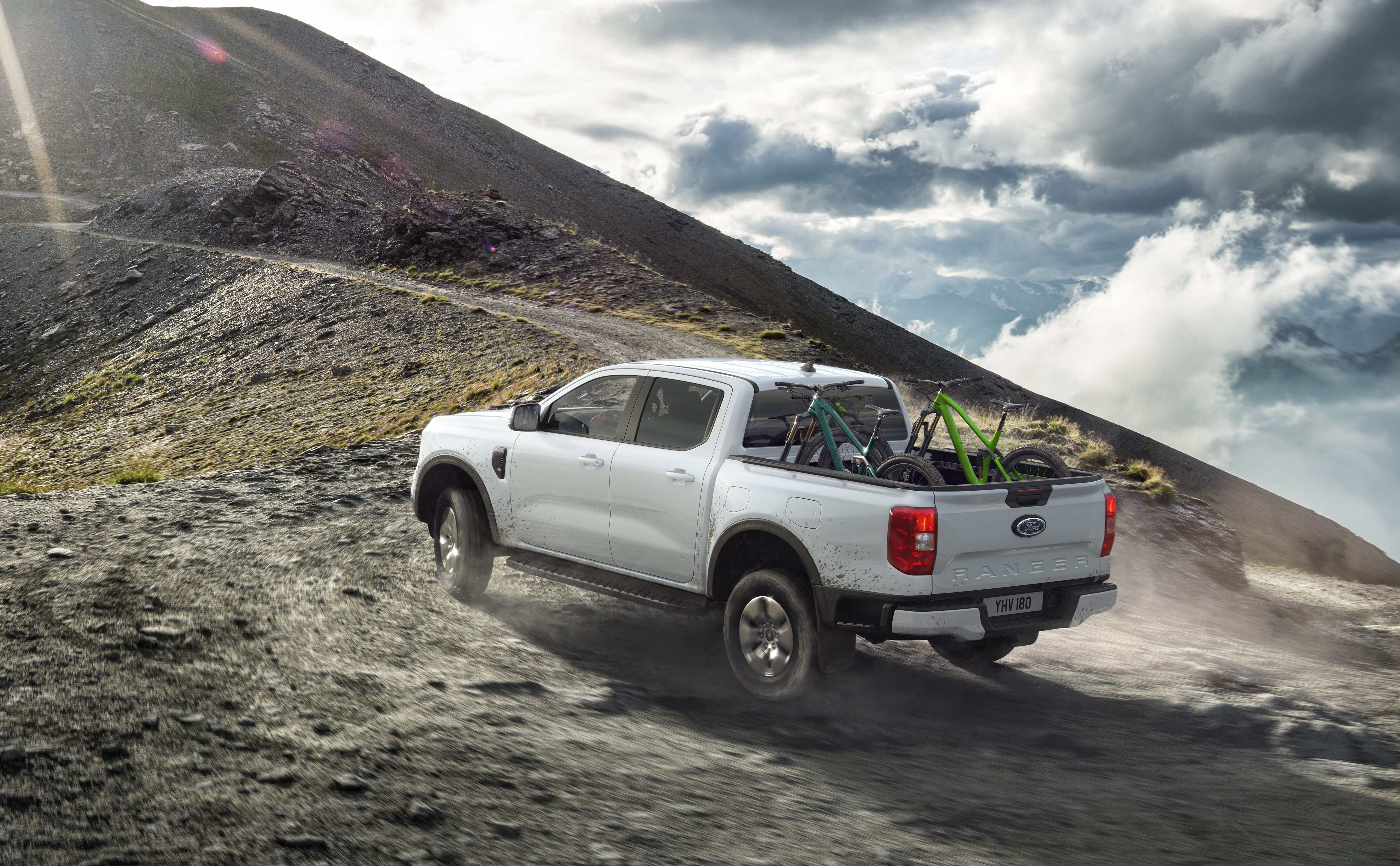a pickup with a bicycle going up a dirt track
