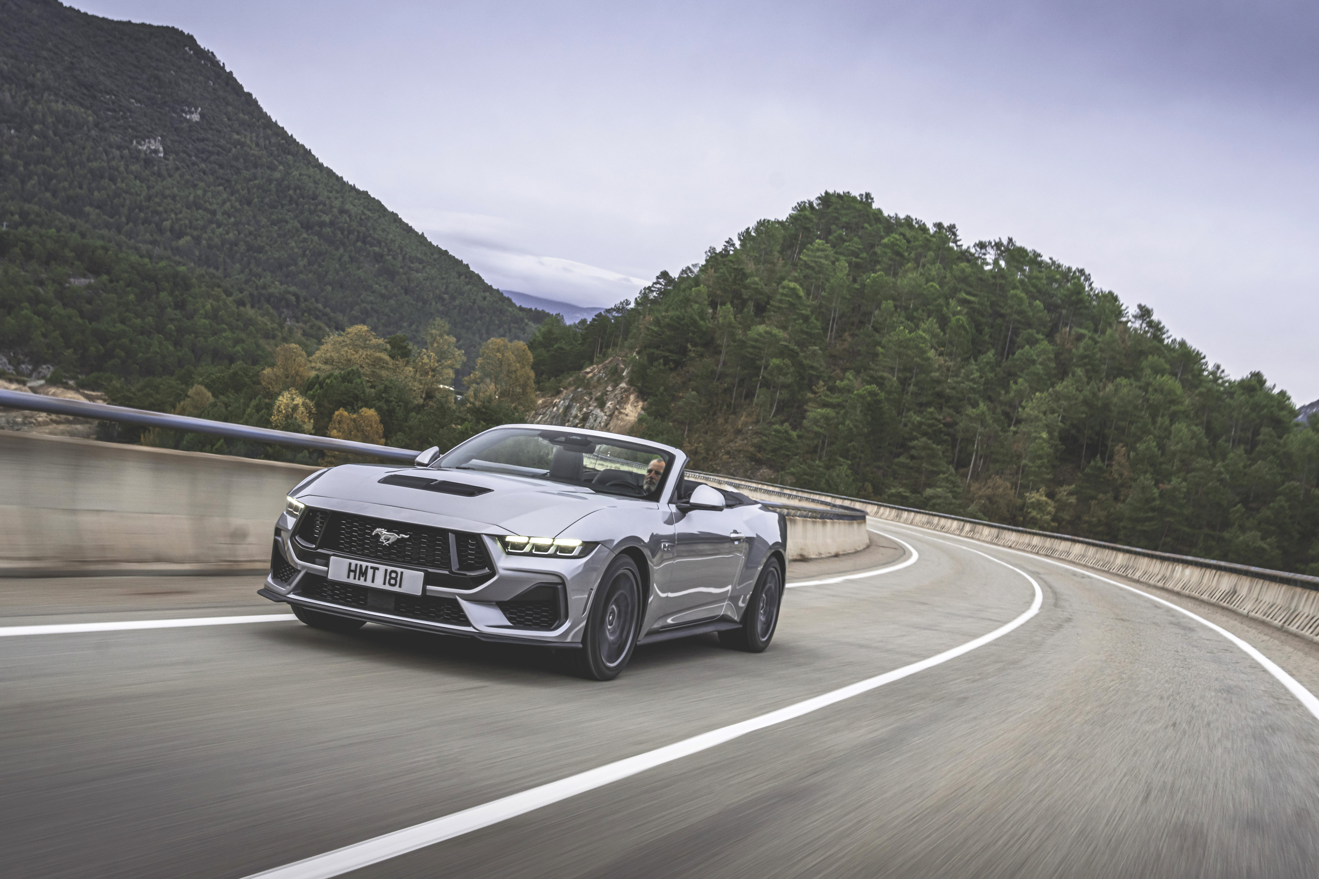 a silver Ford Mustang on curved highway