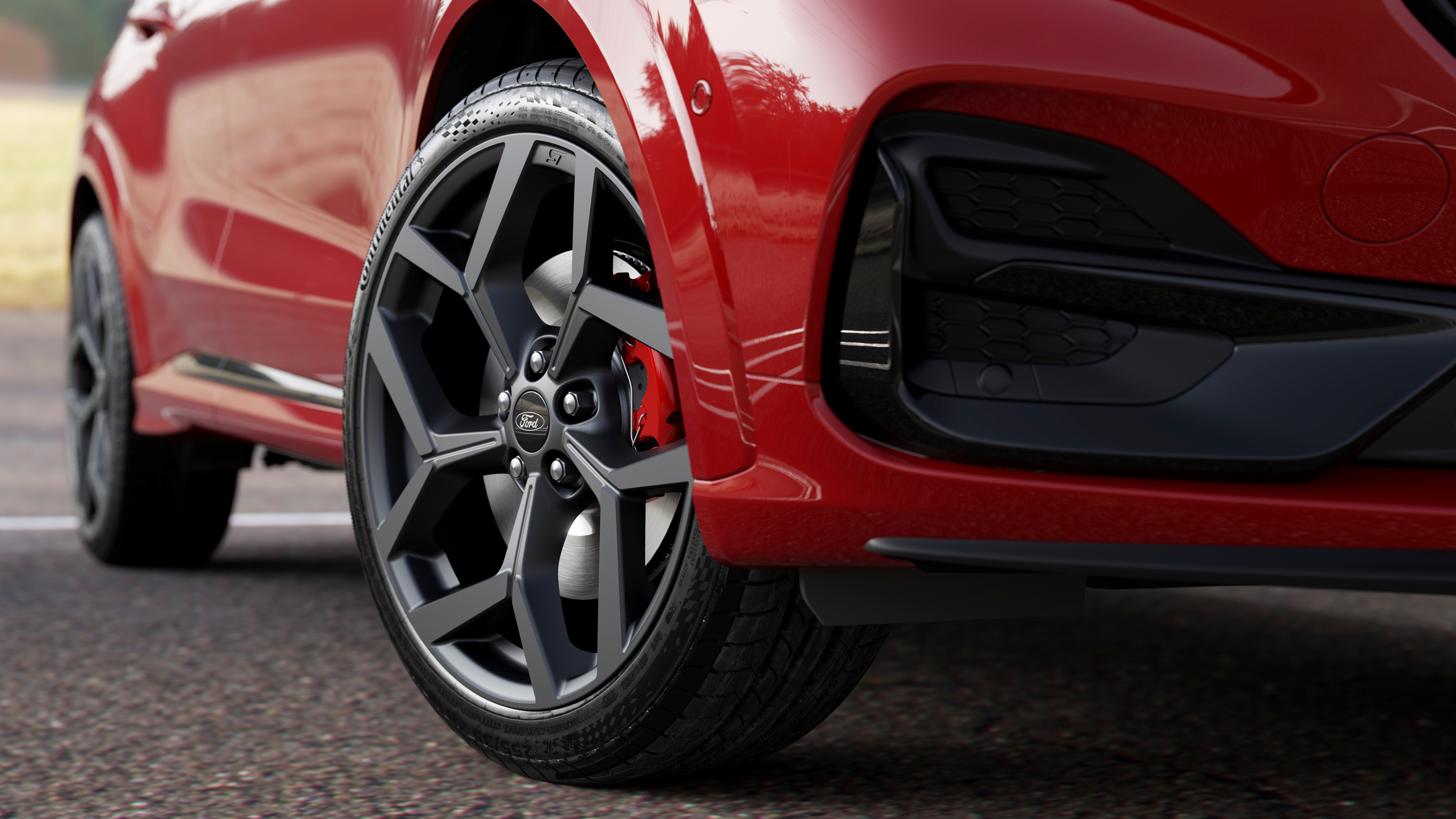 close-up of a red cars tire and grill