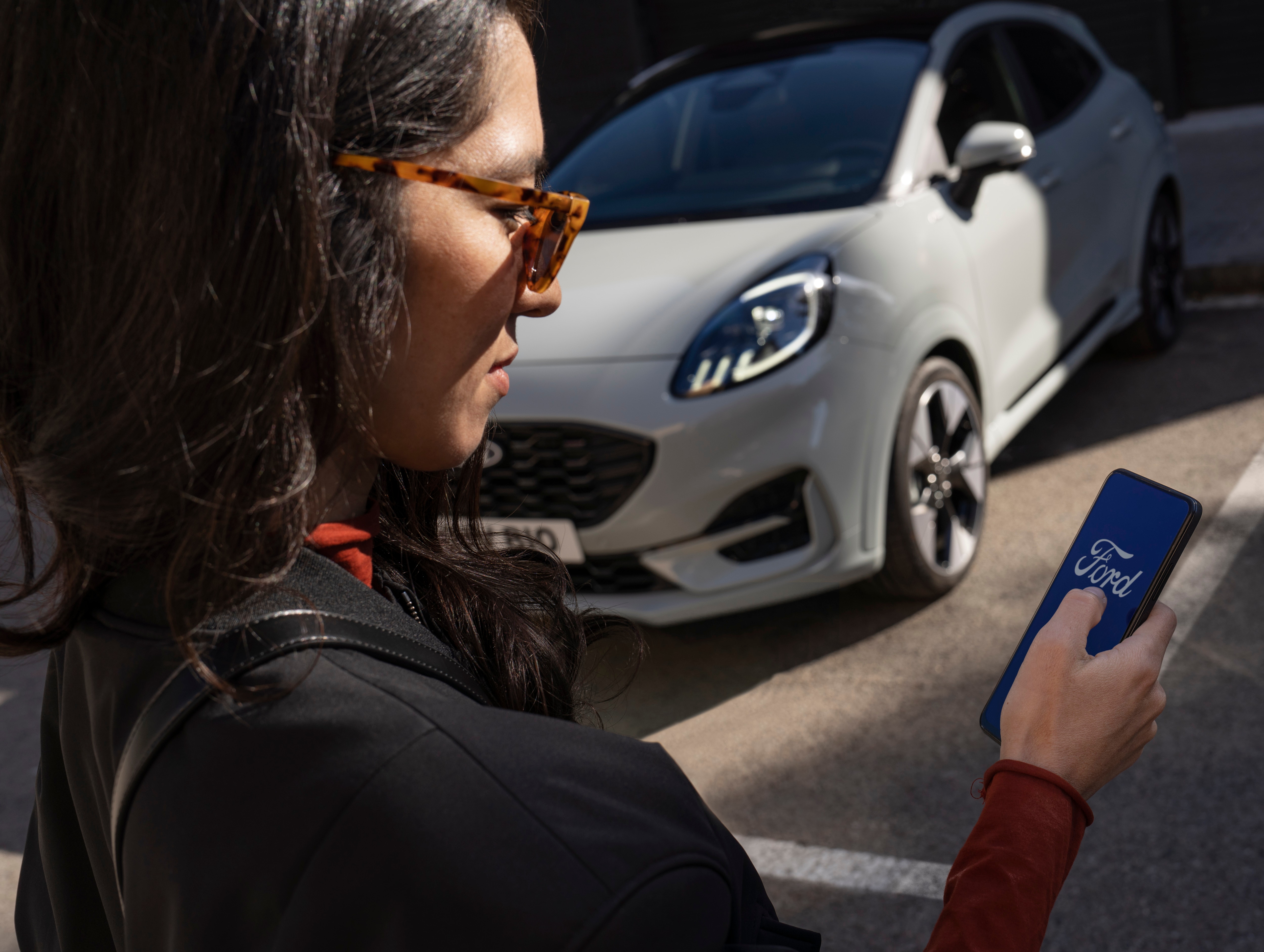 a woman on a phone next to a parked car