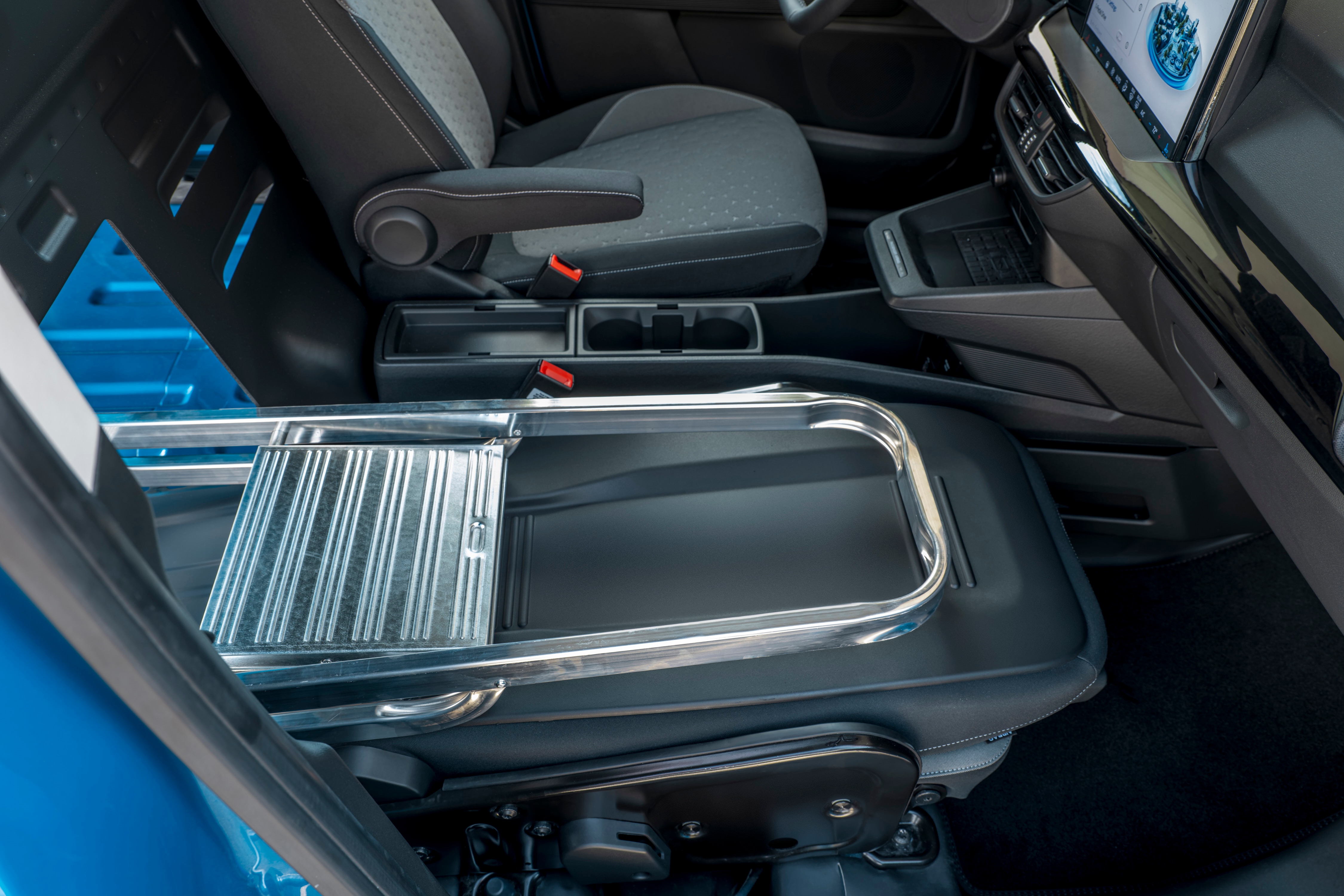Ford E-Transit Courier with load-through bulkhead. Passenger seat is folded flat and a ladder has been loaded through using all the space.