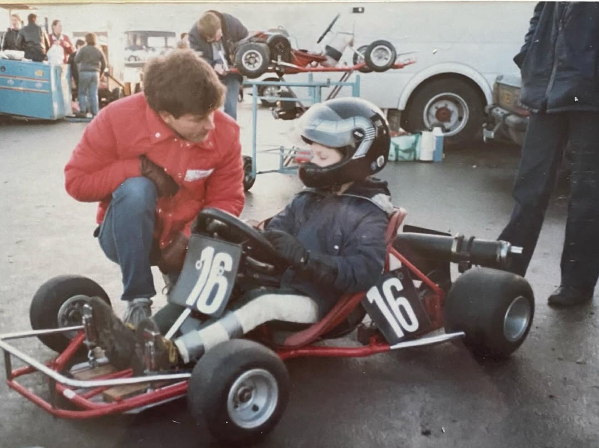 Guy in a red go-kart with number 16 on, parked up waiting to go out for his first race