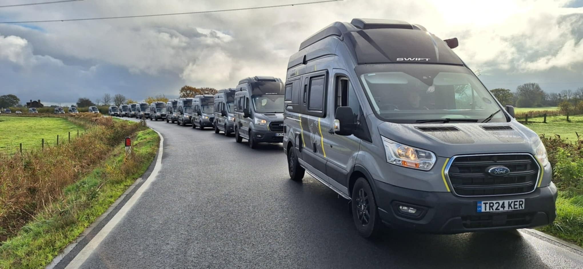 Convoy of Transit Trail-based Trekker camper vans on a winding country road