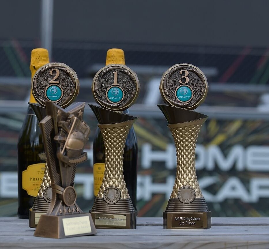 Swift-branded trophies and prosecco bottles on the podium at a kart track