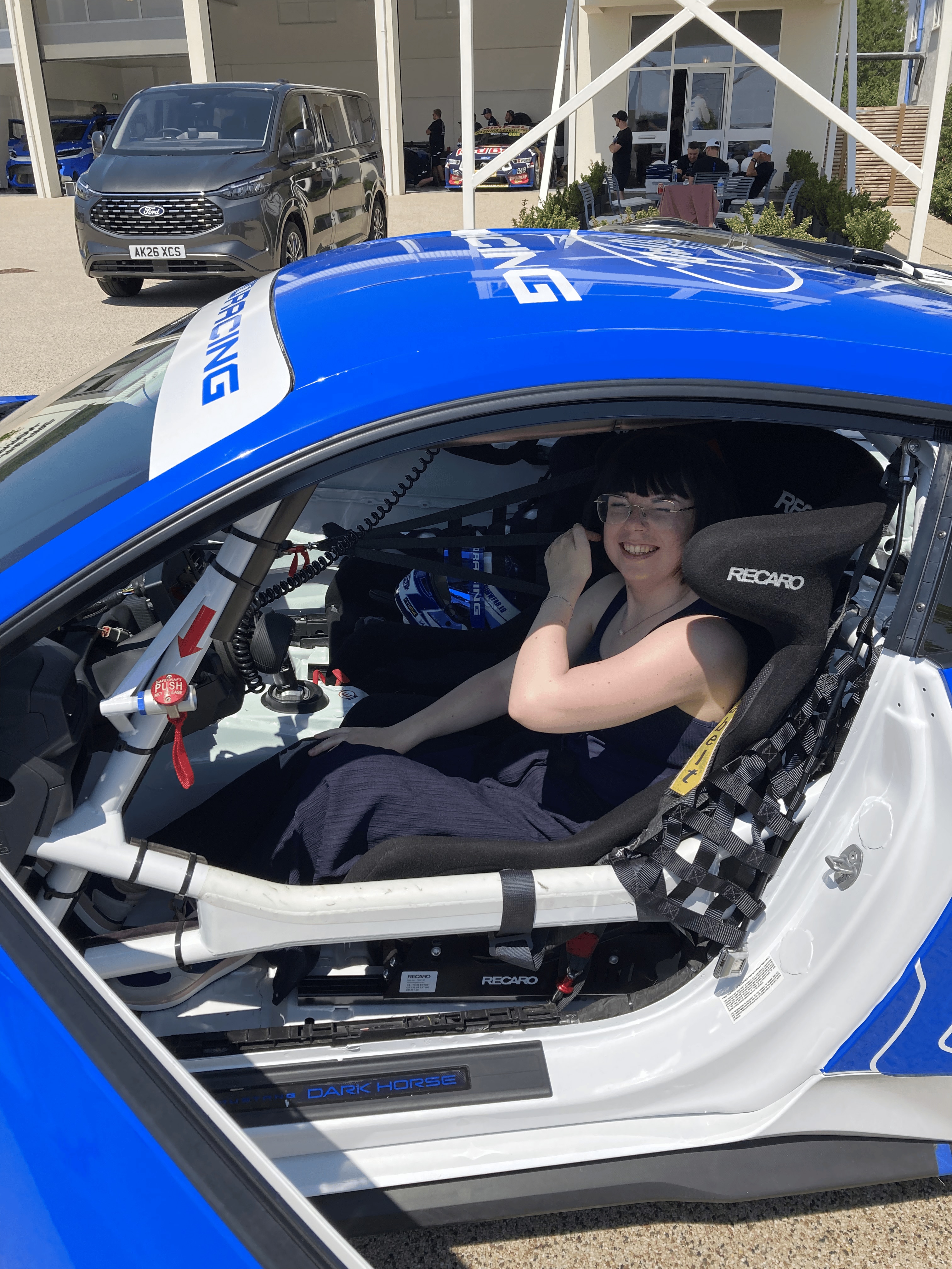 Rebecca experiencing being in the driver's seat in a Ford Racing livered Mustang Dark Horse R.