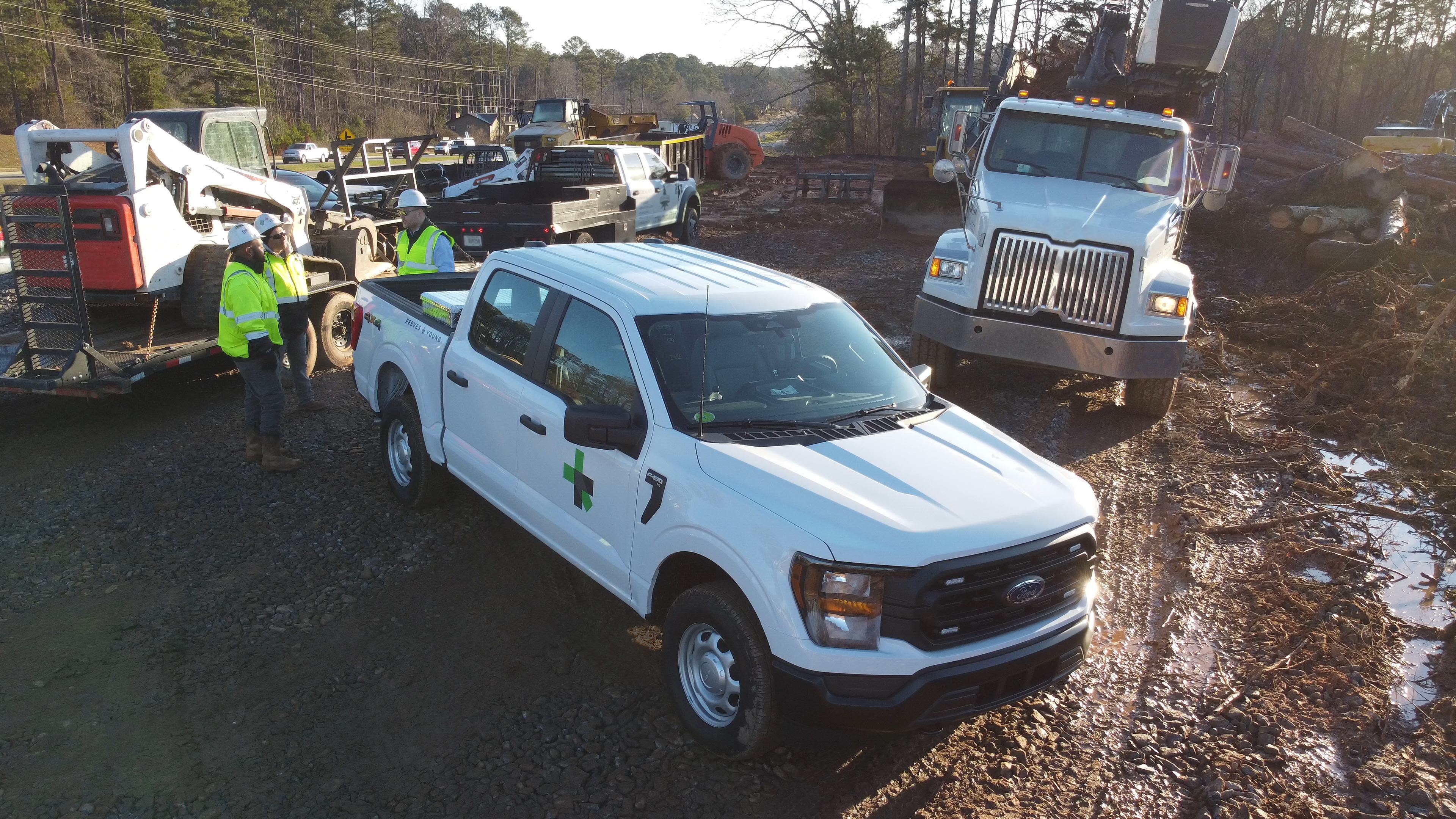 A Ford F-150® truck parked at a muddy construction site, surrounded by workers and equipment.