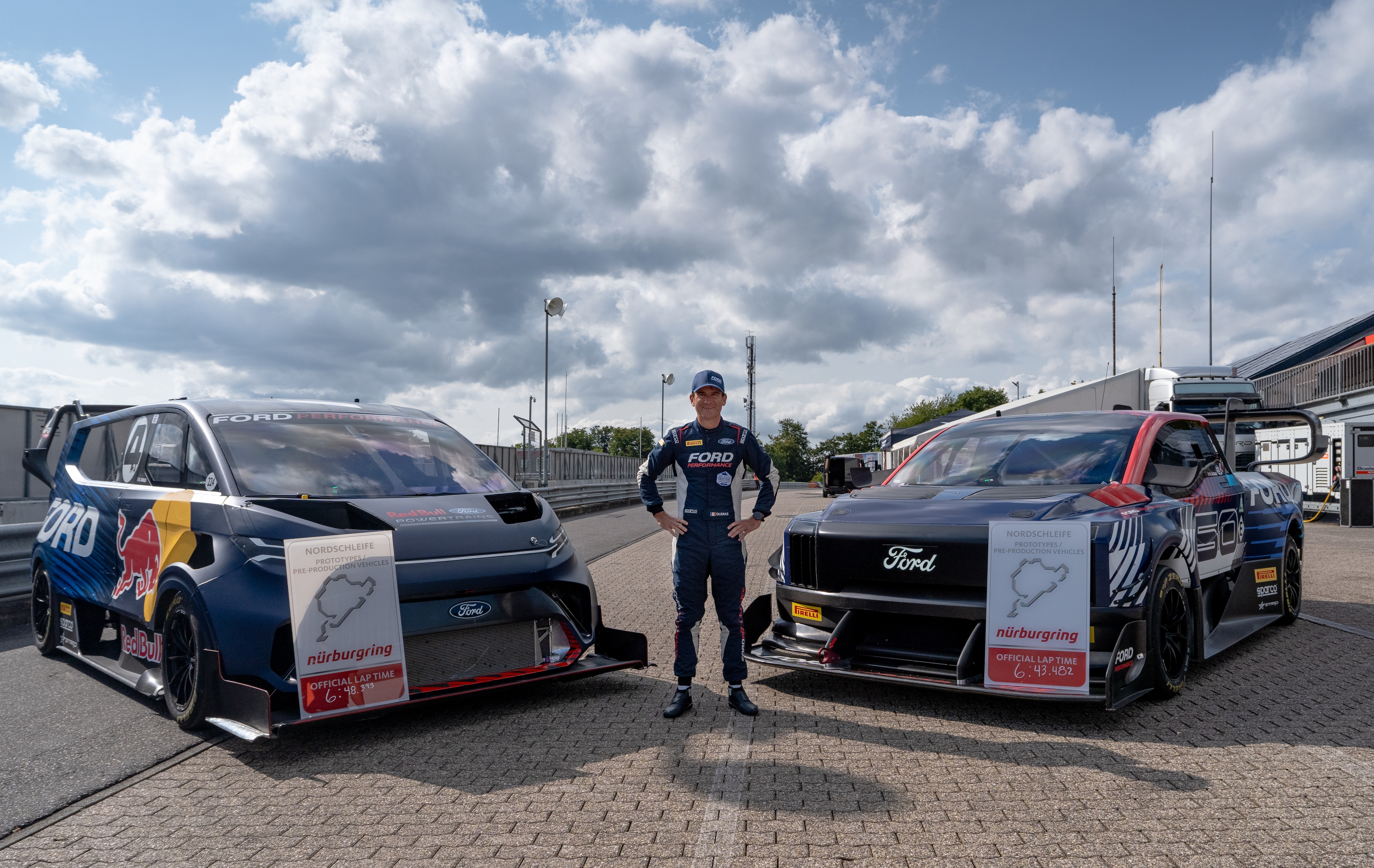 A man poses between two Ford motorsports vehicles.