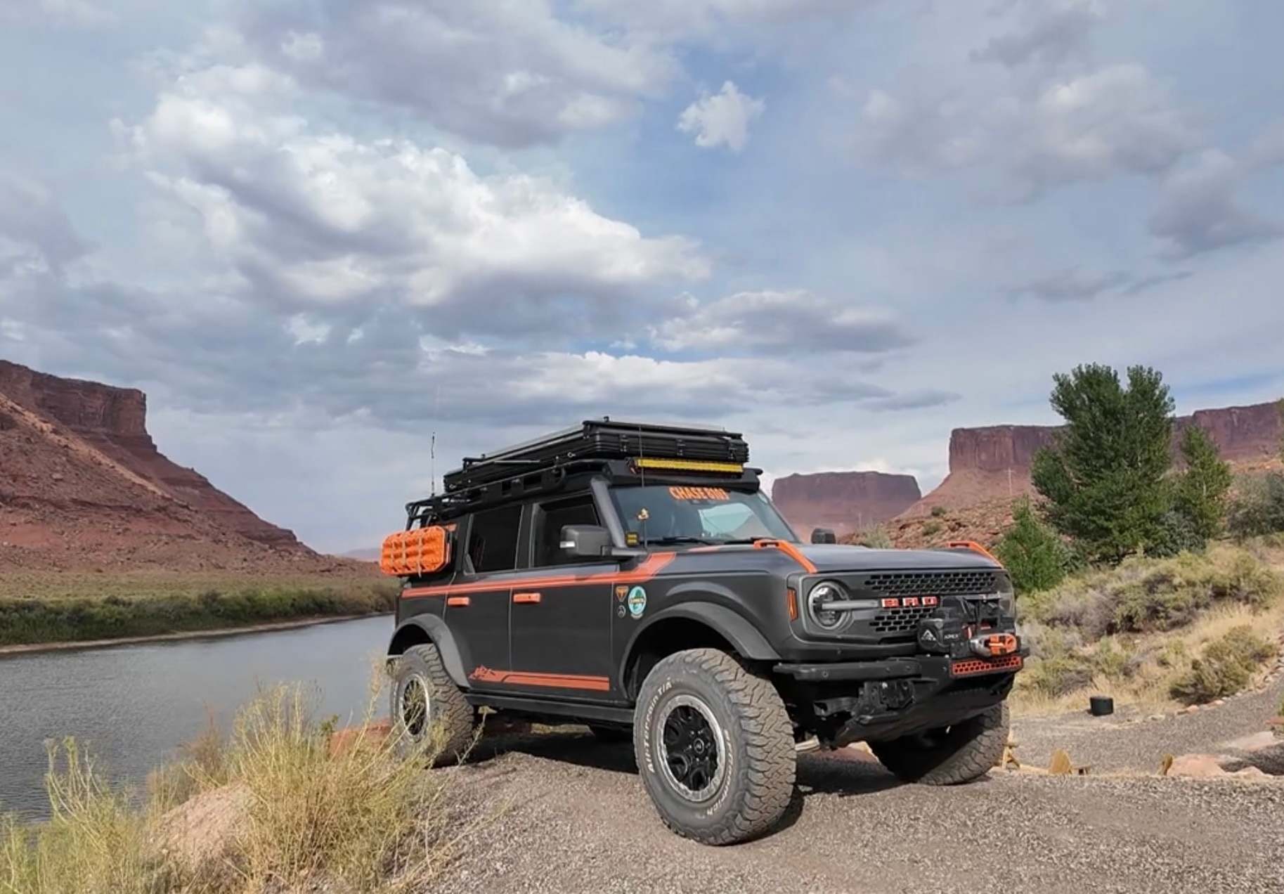 A Ford Bronco parked in front of the Colorado River.