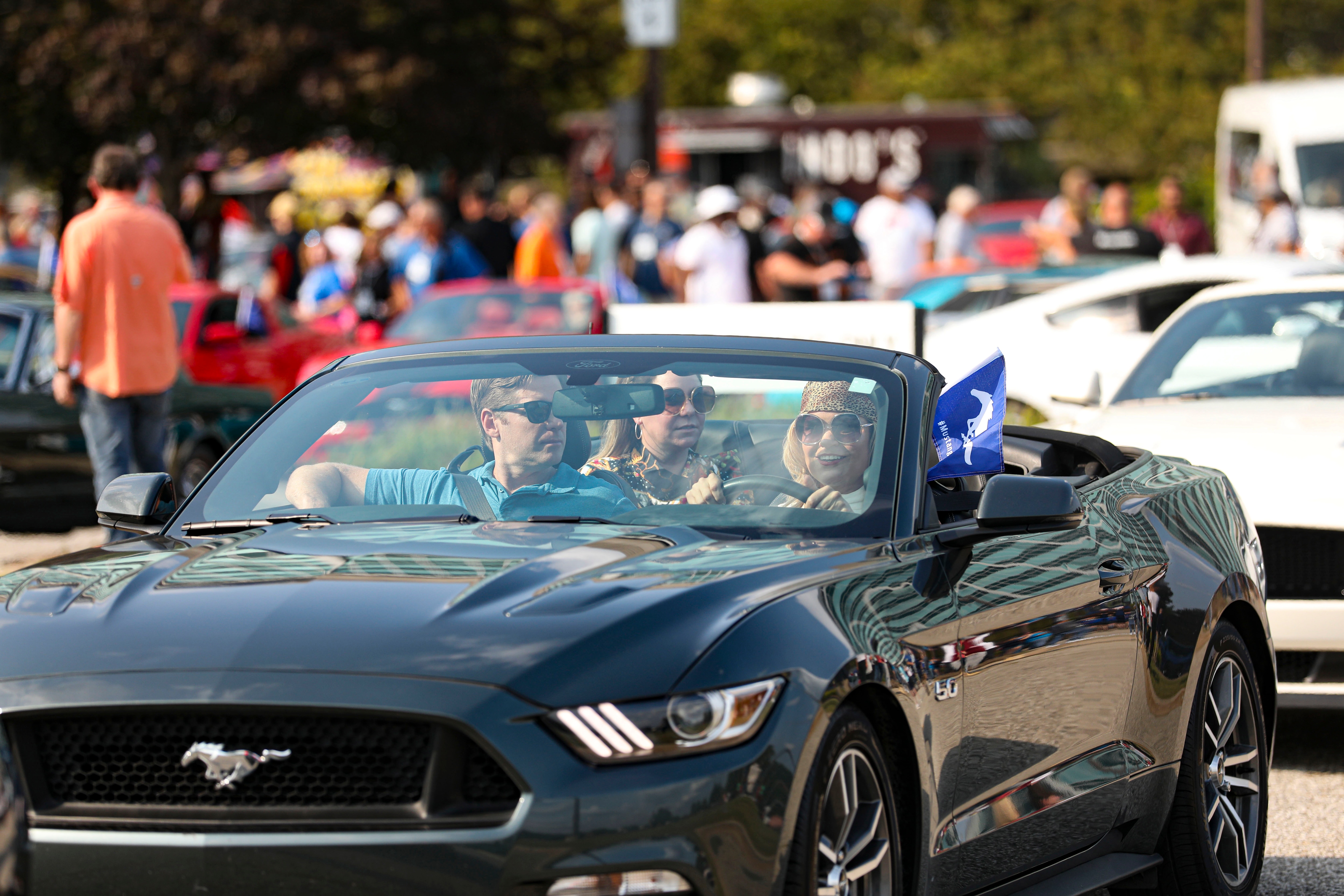 A woman dressed in 1960s-inspired clothing drivers her Mustang at The Stampede celebration at Ford World Headquarters in Dearborn, Michigan on Sept. 14, 2022.