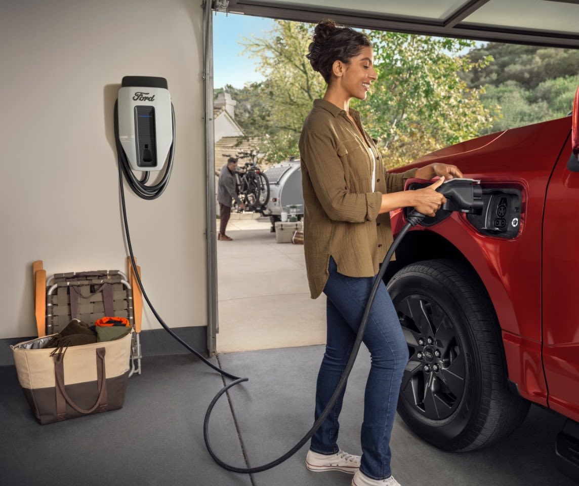 A woman plugging in an F-150® Lightning® truck to charge in a garage.