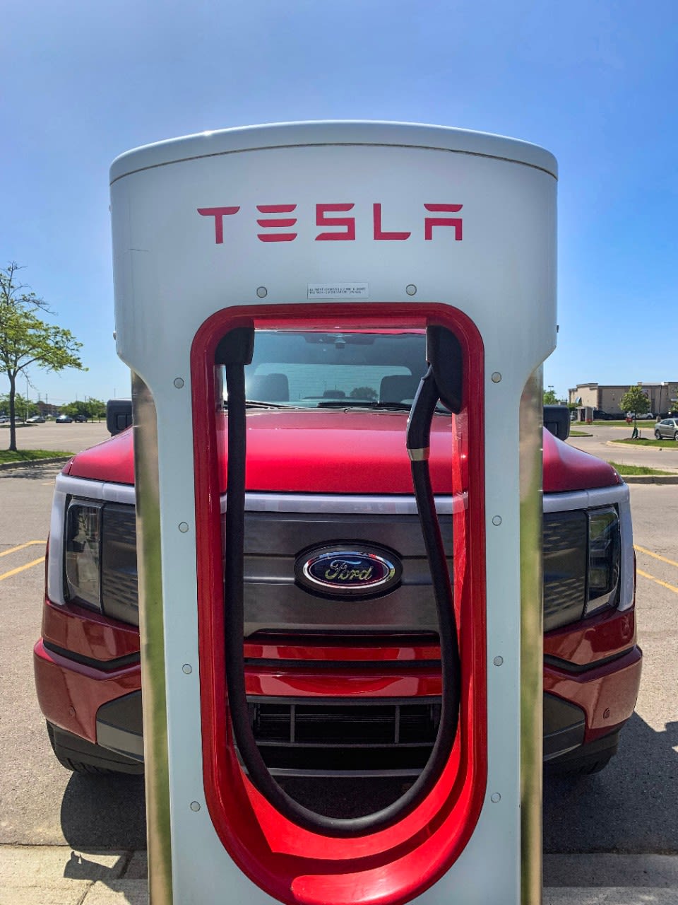 An F-150® Lightning® parked in front of a Tesla Supercharger.
