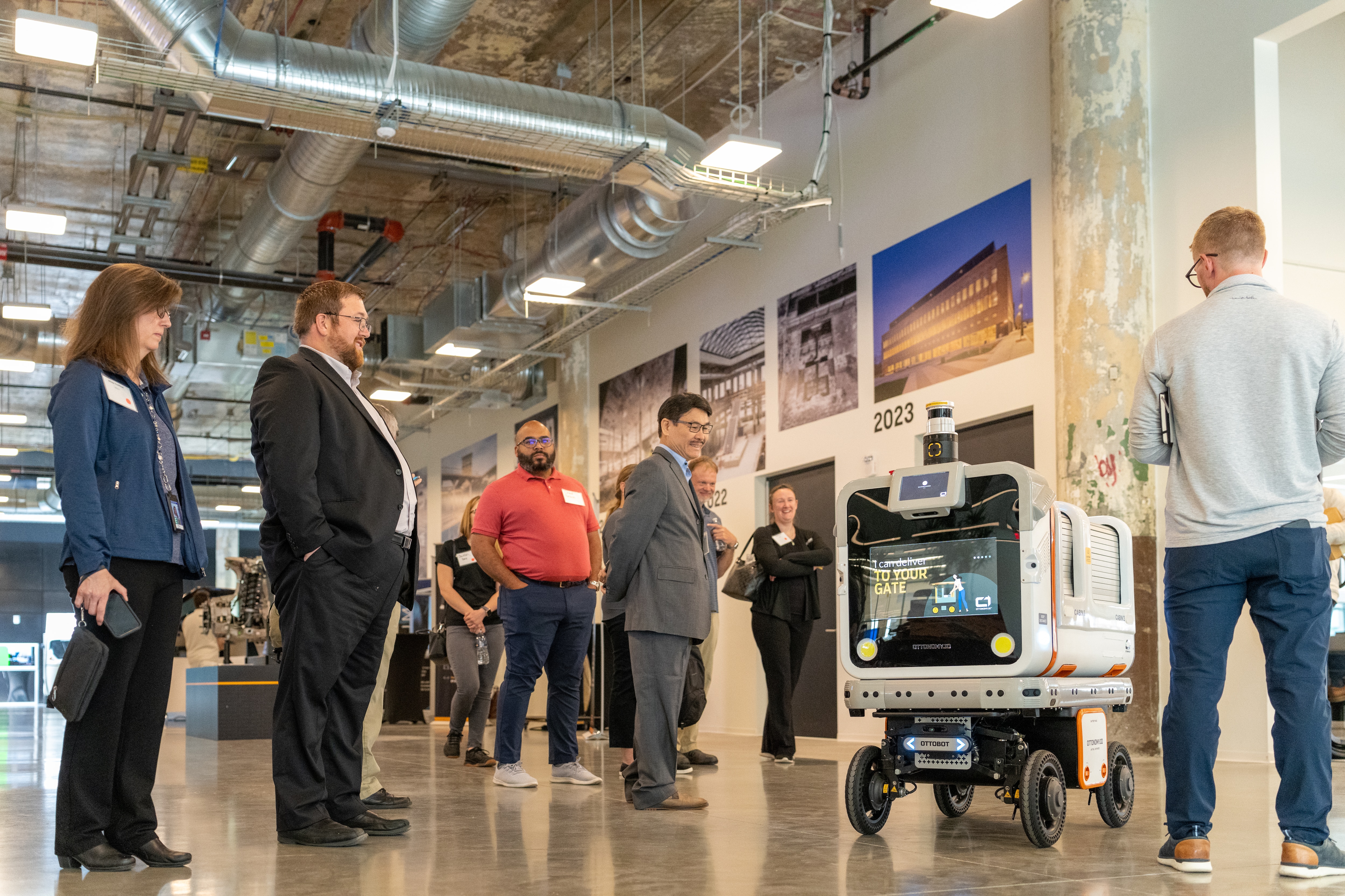 A group of people gather around a piece of technology at an innovation hub