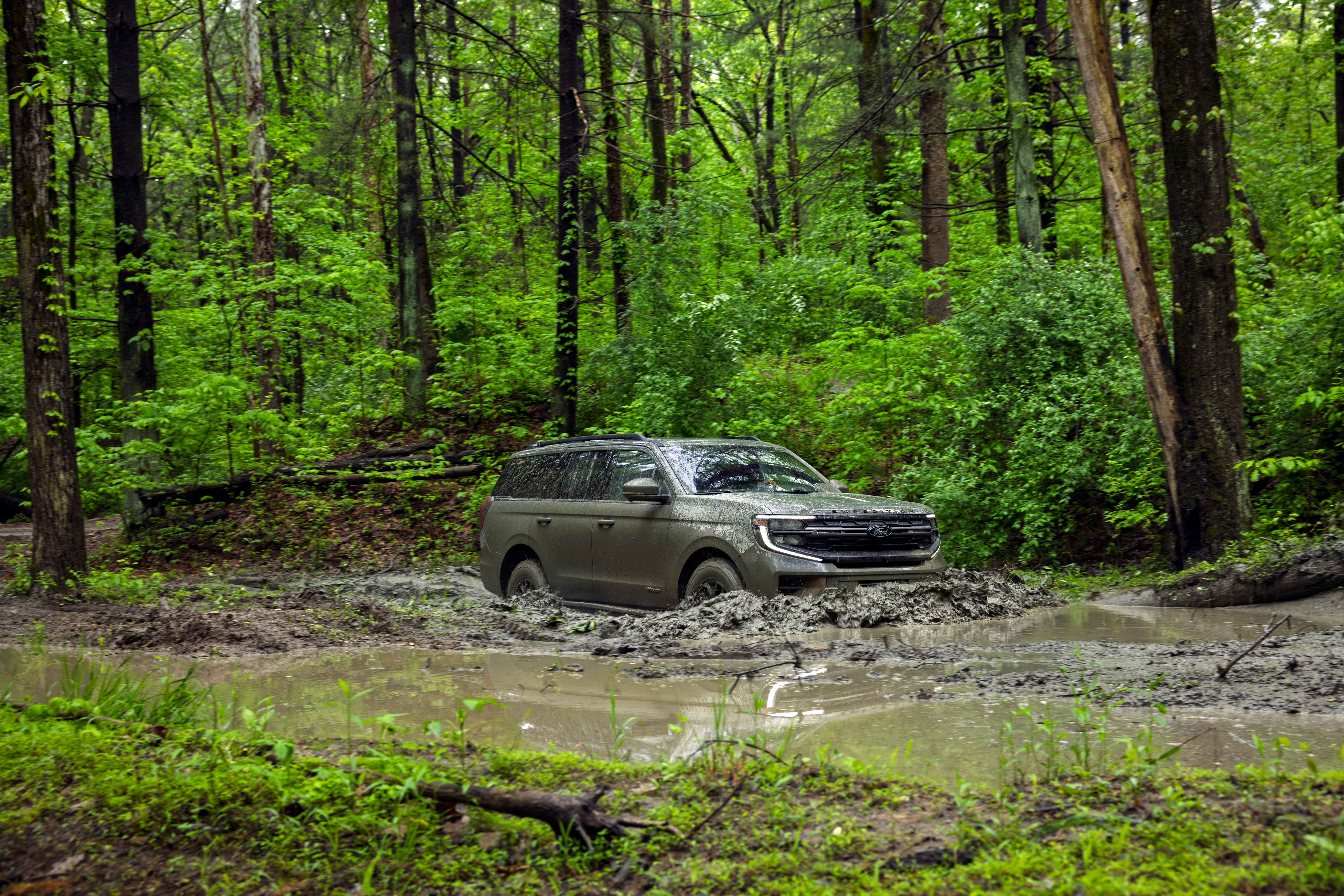 2025 Ford Expedition Tremor in a forested area, driving on rugged terrain through a shallow creek