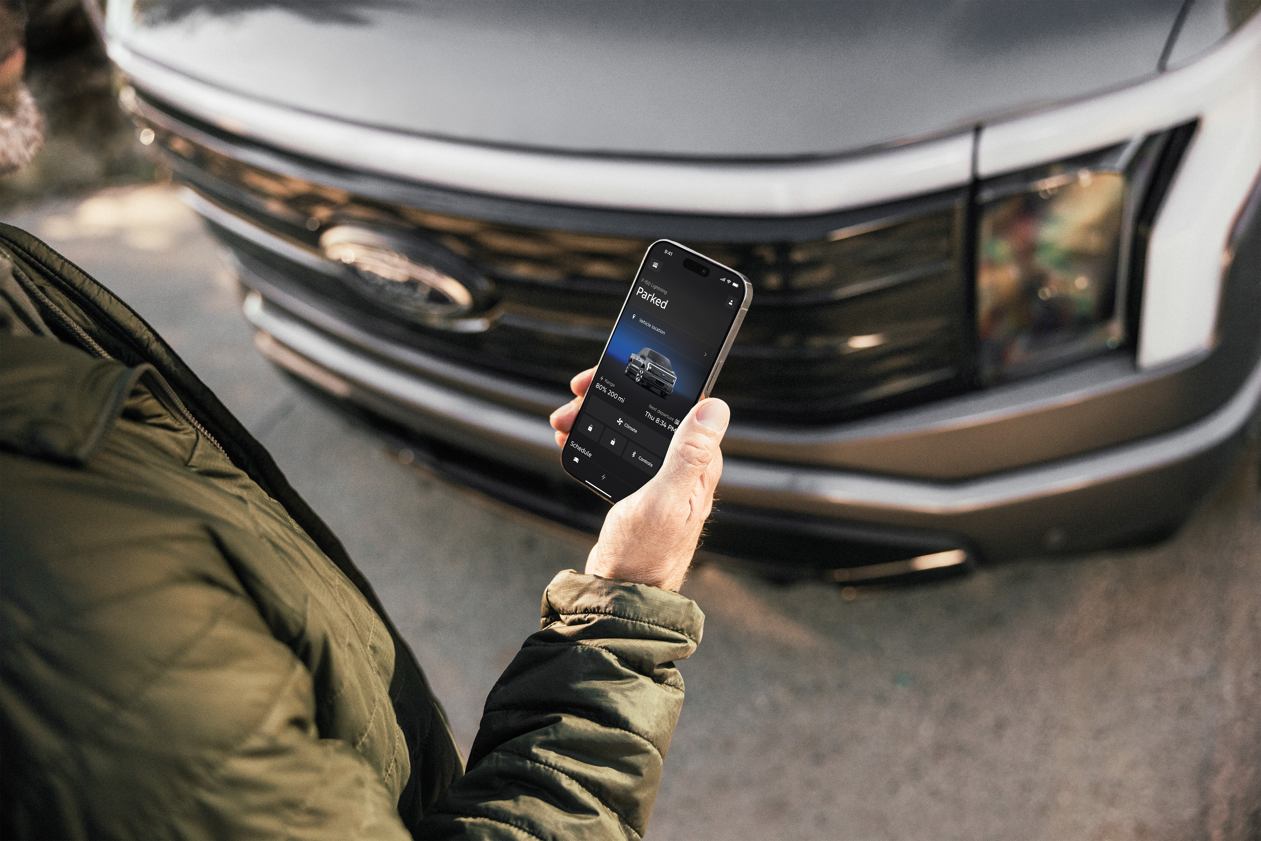 A hand holding a phone. The front of a truck is in the background.