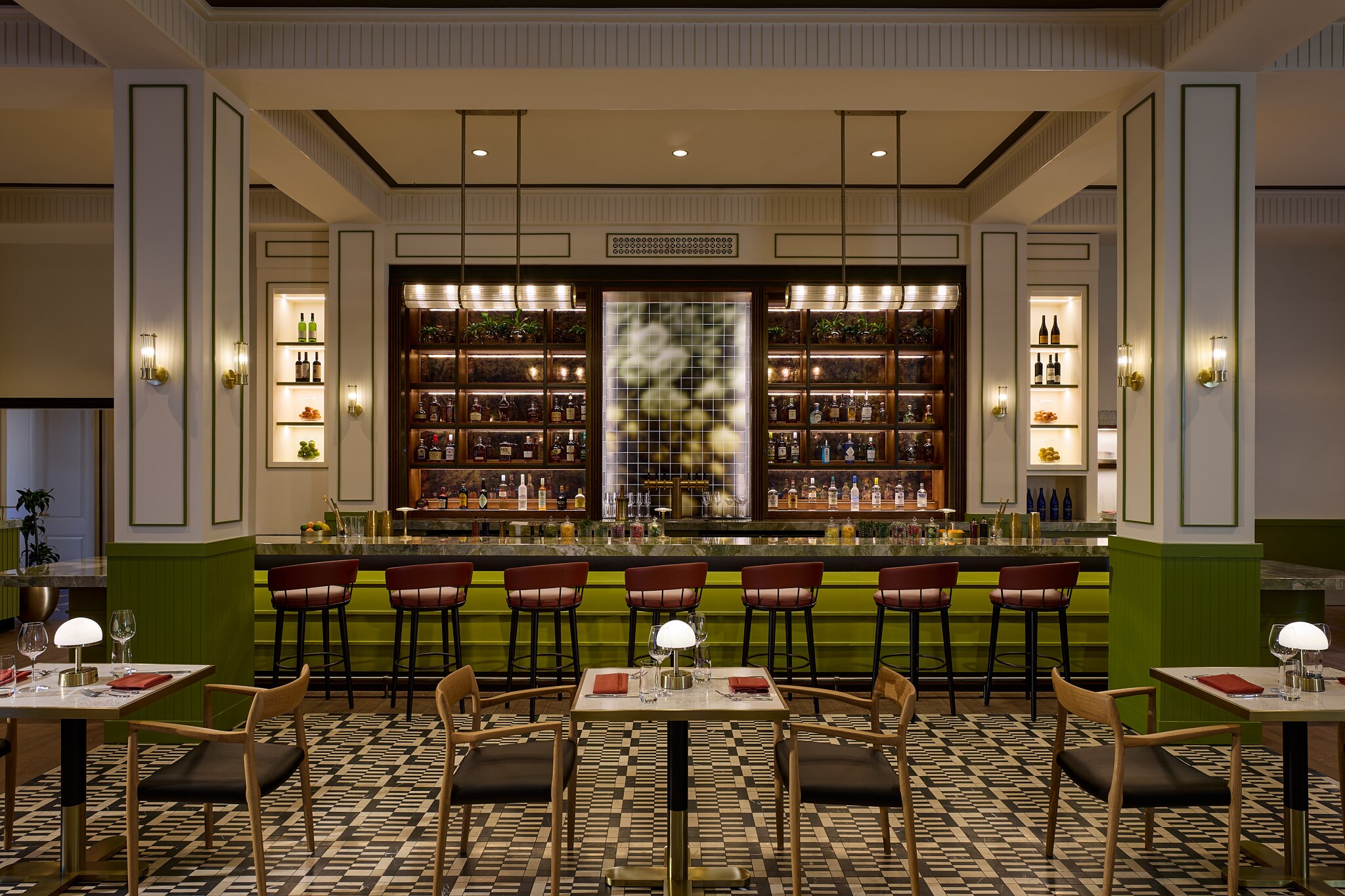 A restaurant in the newly renovated Dearborn Inn shows a low-lit, spacious area with dining tables and a fully stocked bar