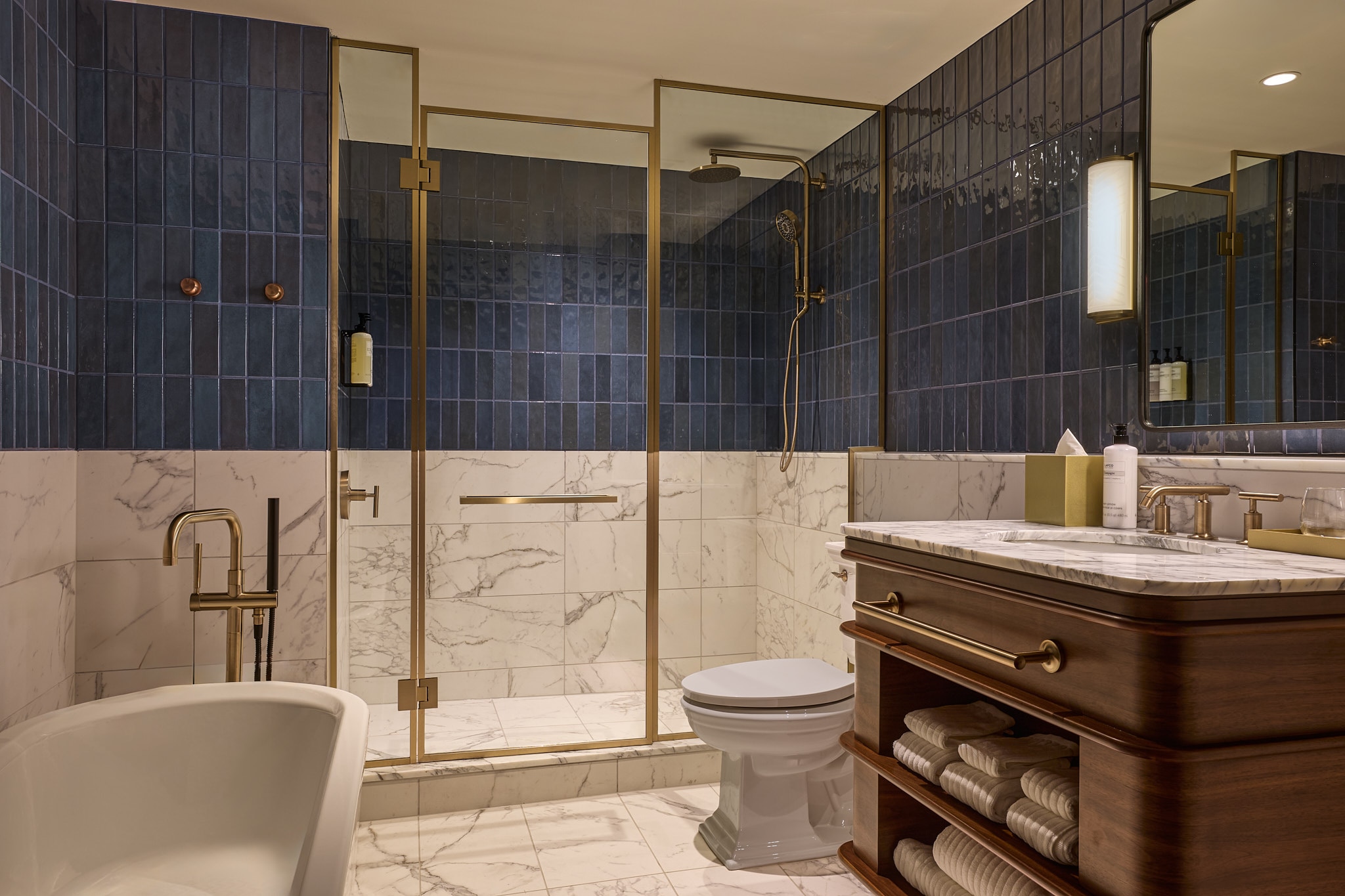A bathroom in the newly renovated Dearborn Inn with blue and white walls, white appliances, a wooden vanity and an overall luxurious feel