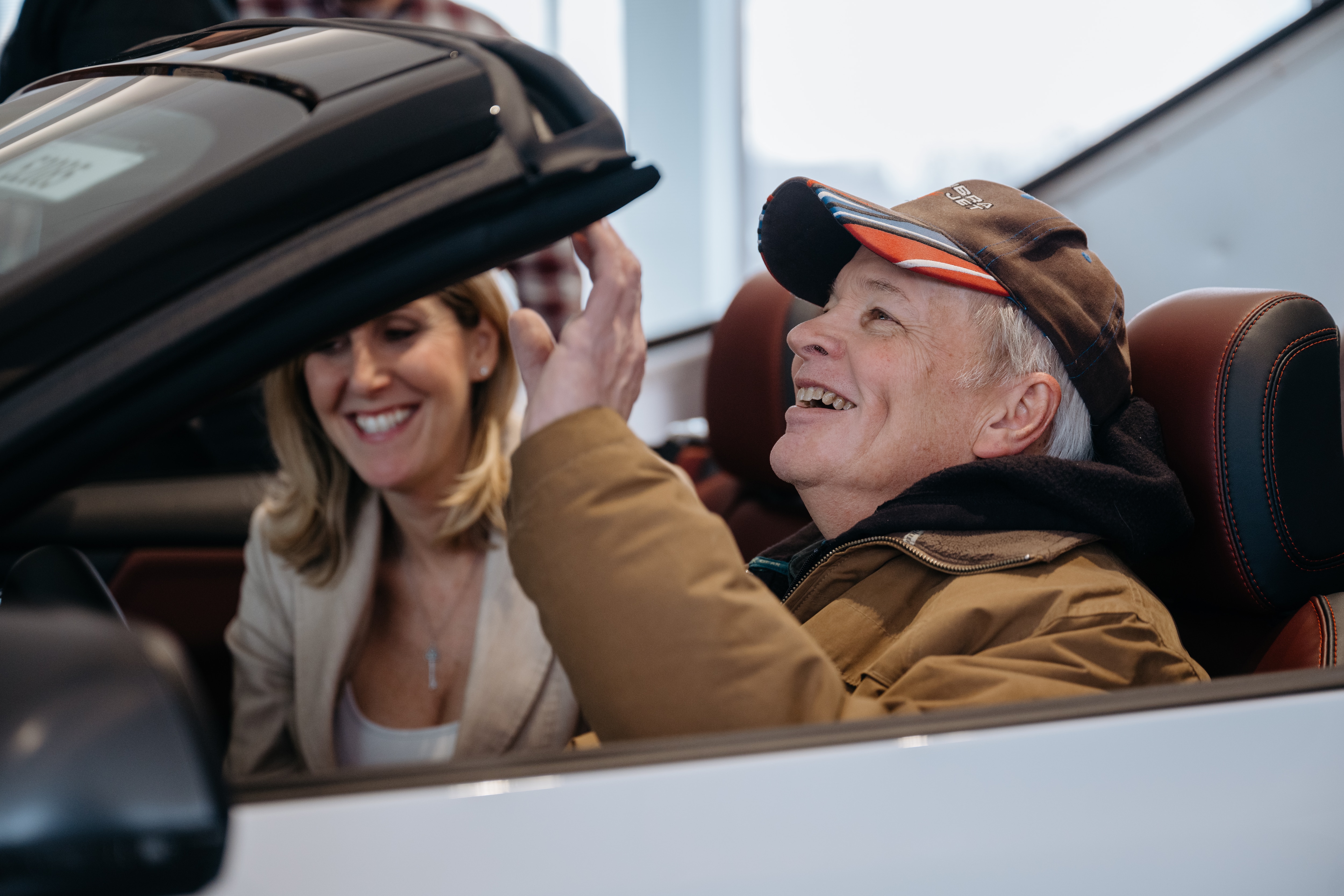 A man sits in a convertible, smiling excitedly.