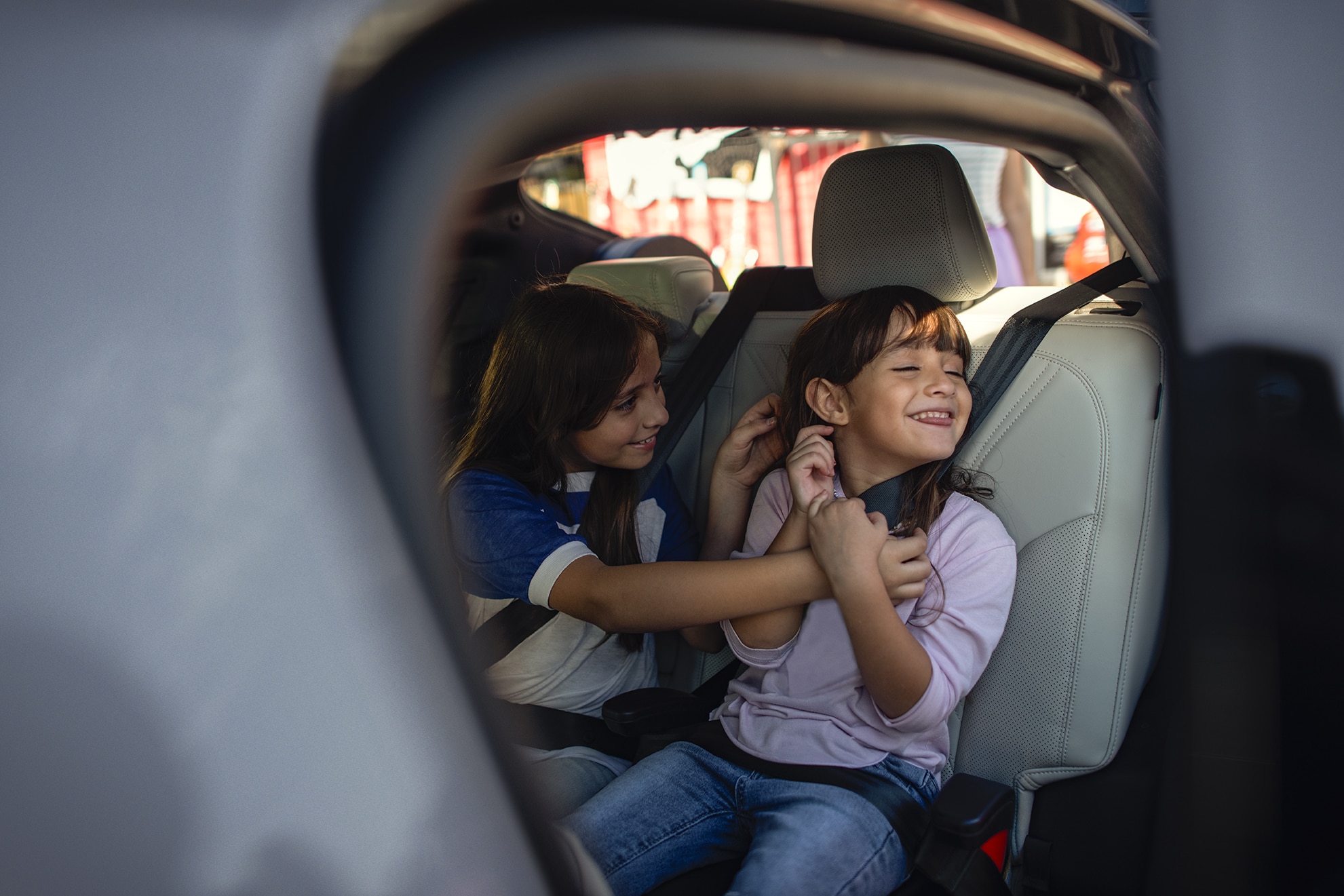 Two children sit smiling in a vehicle.