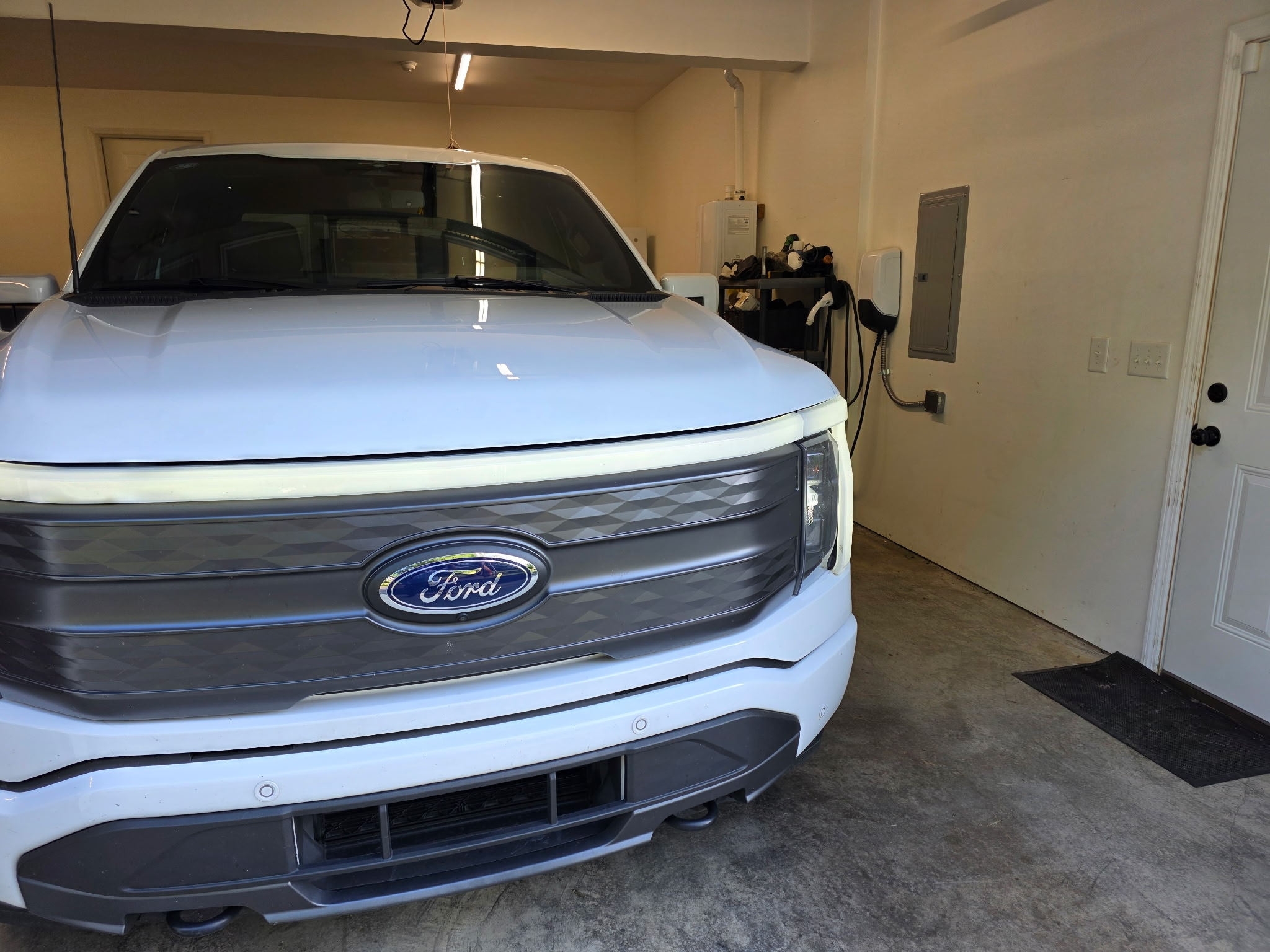 A white F-150 Lightning truck charges in a garage.
