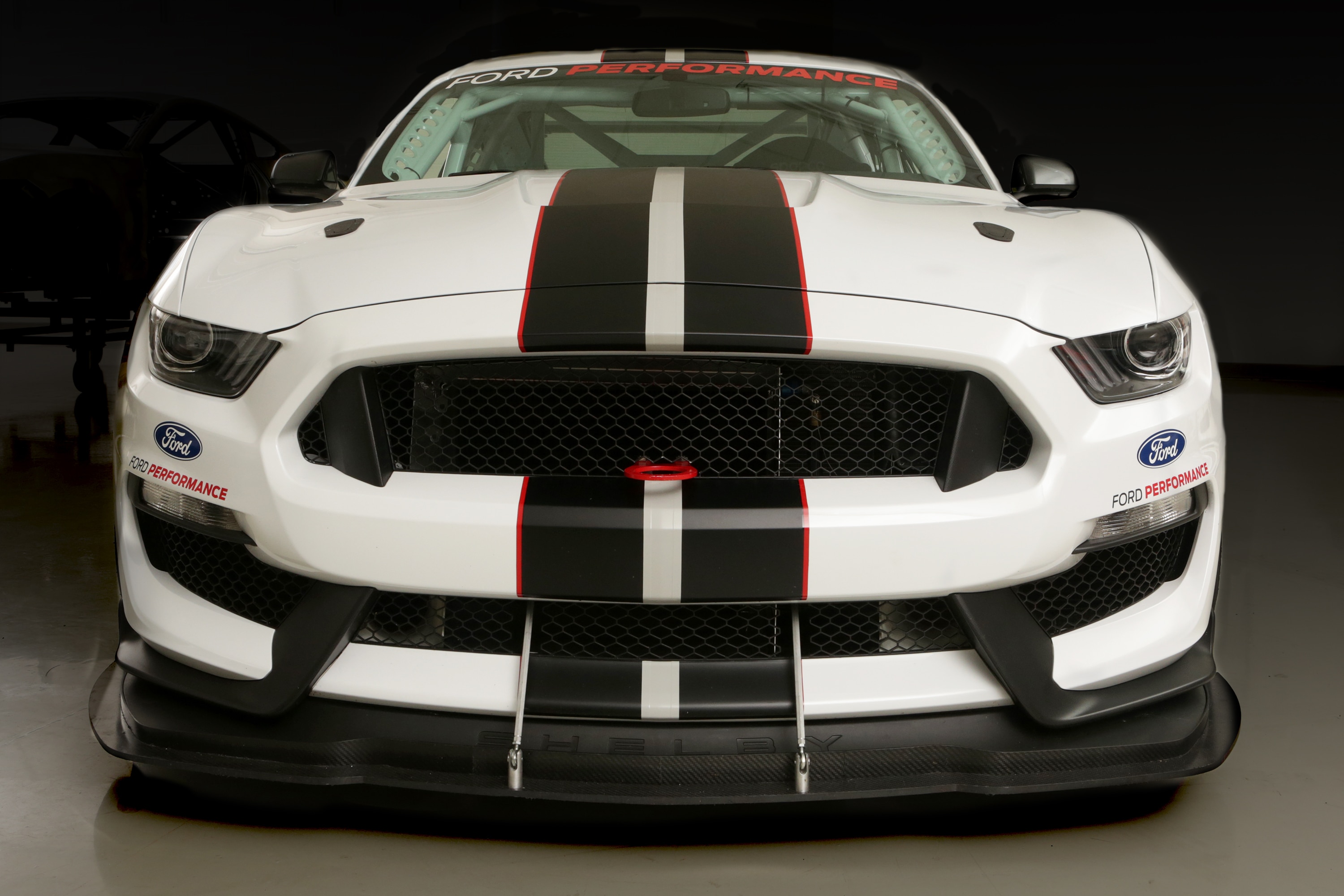 A white Mustang with two stripes down the middle viewed from the front.