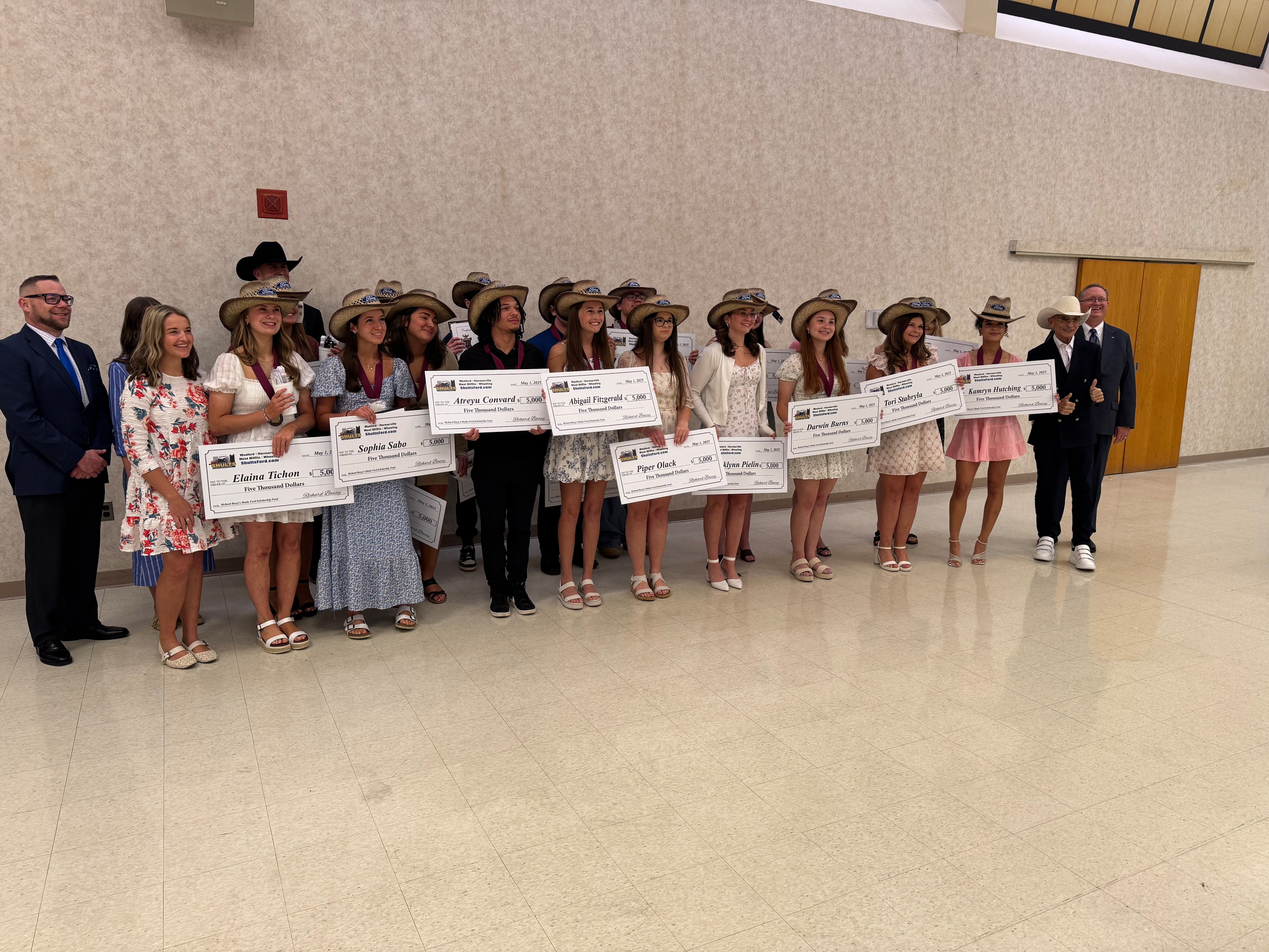 A group of high school students pose for a photo, holding up the recently awarded scholarship checks they've been given