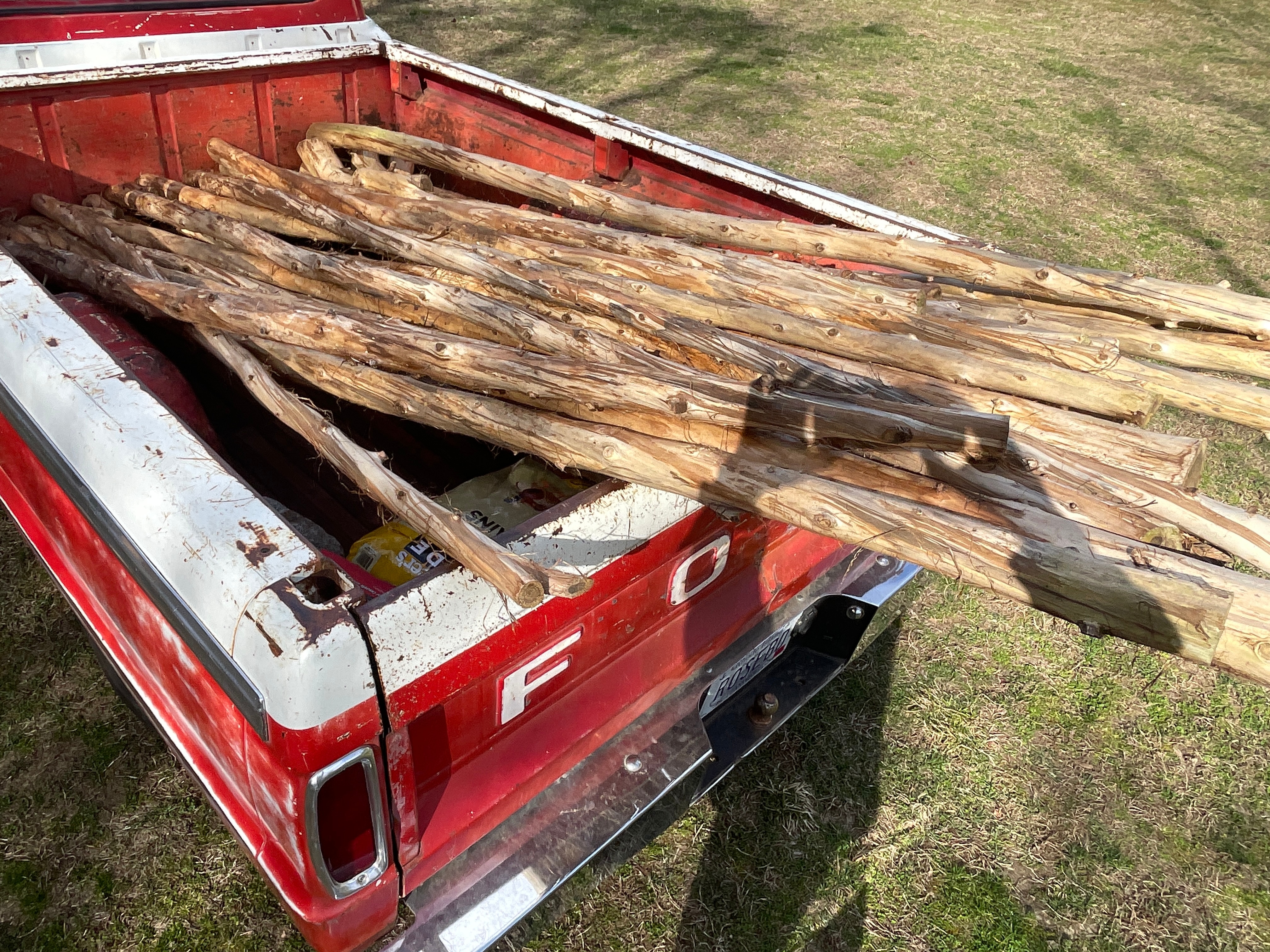 Lumber piled in the bed of a vintage red truck.