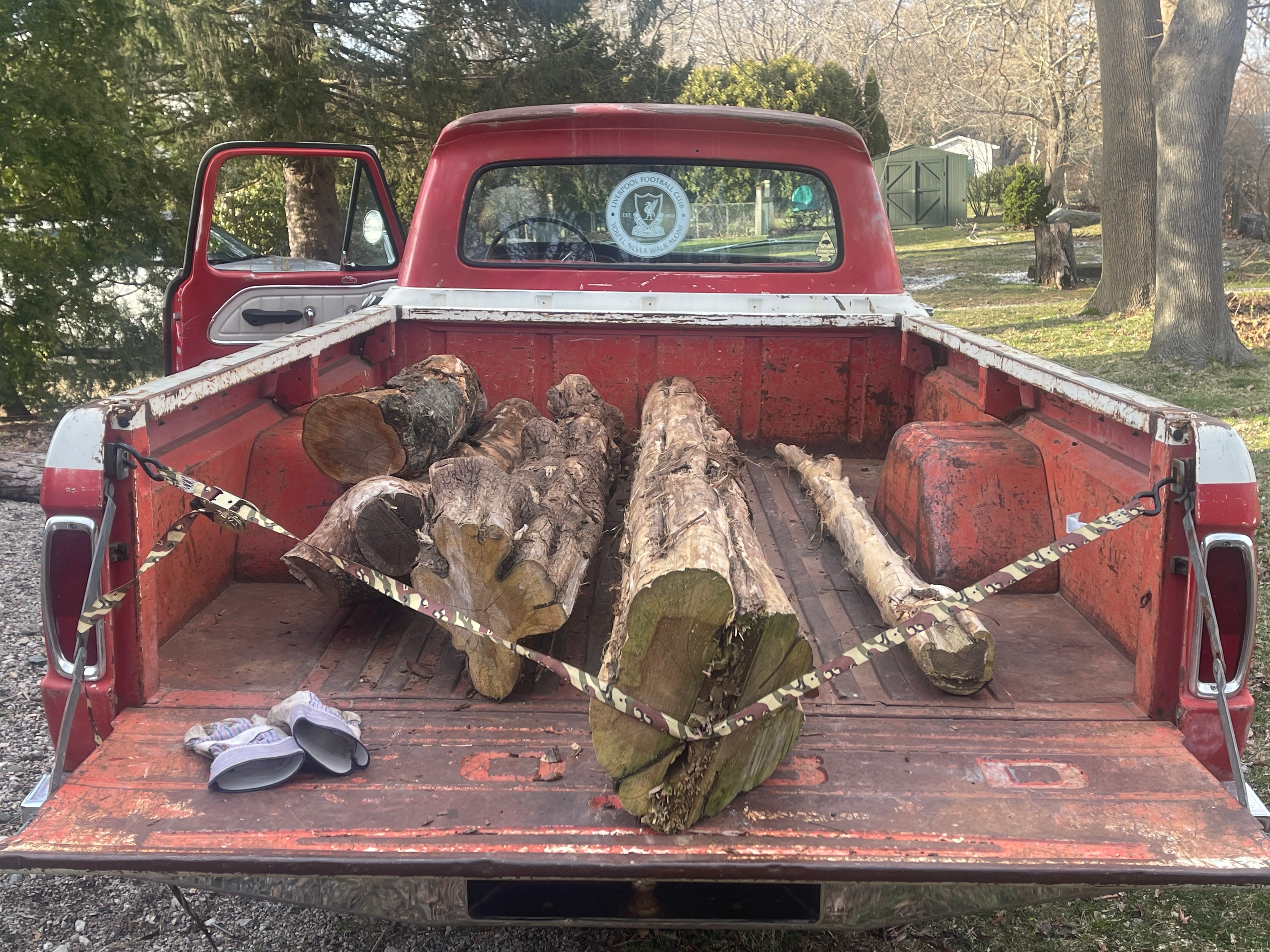 Lumber piled in the bed of a vintage red truck.