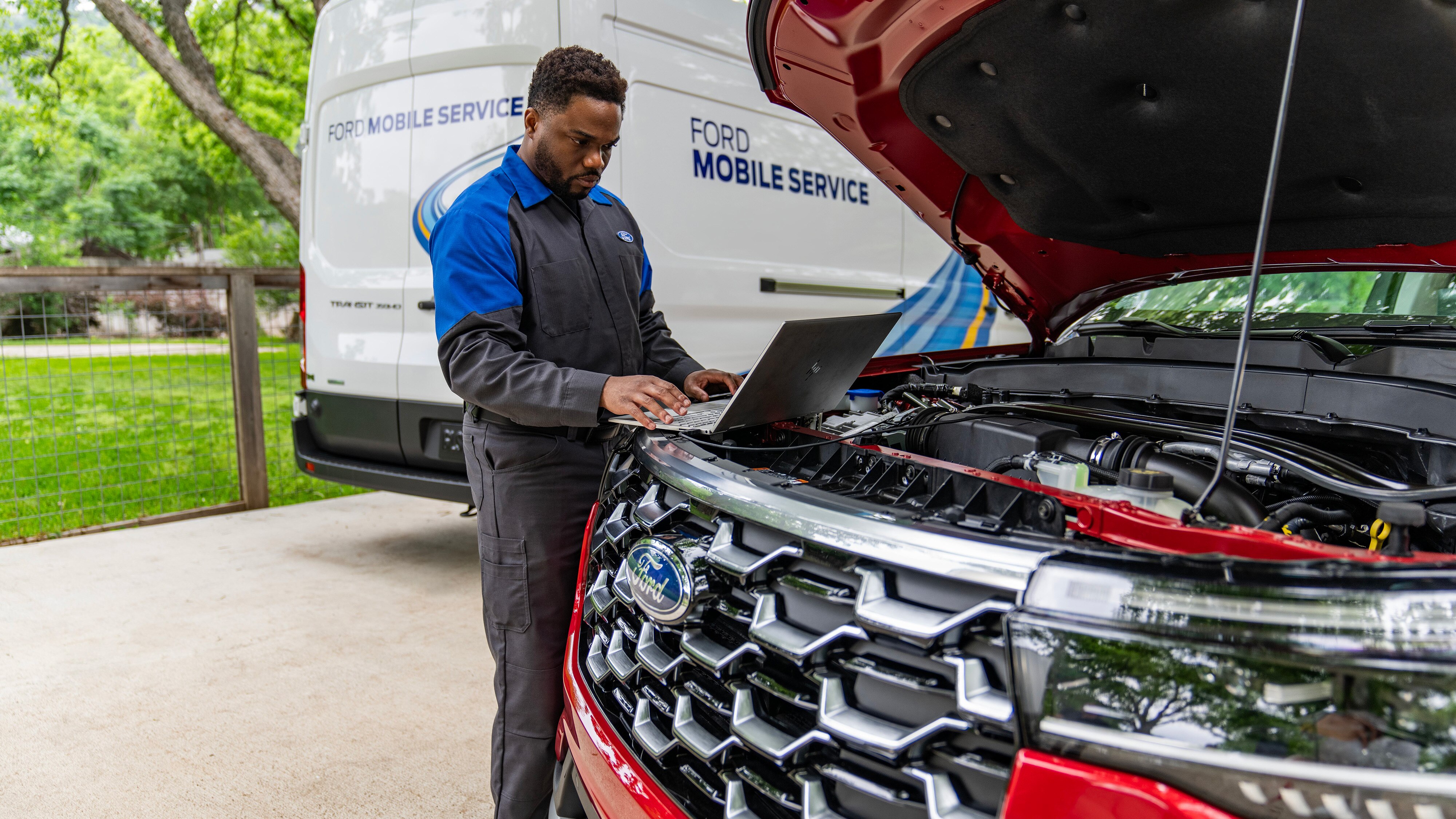 A Ford Mobile Service tech works on a Ford vehicle in a driveway.