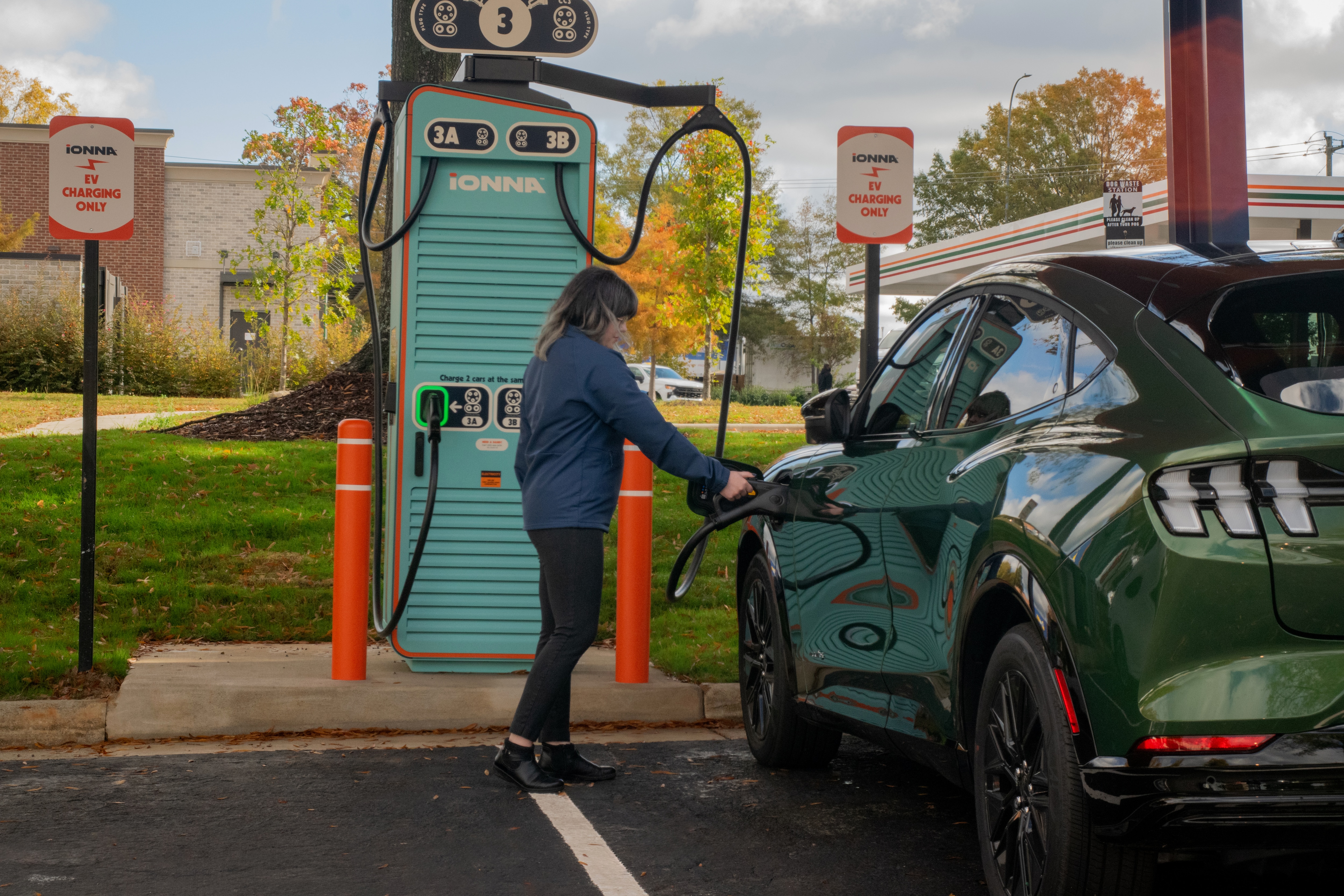 A woman charging an electric vehicle at an IONNA station.