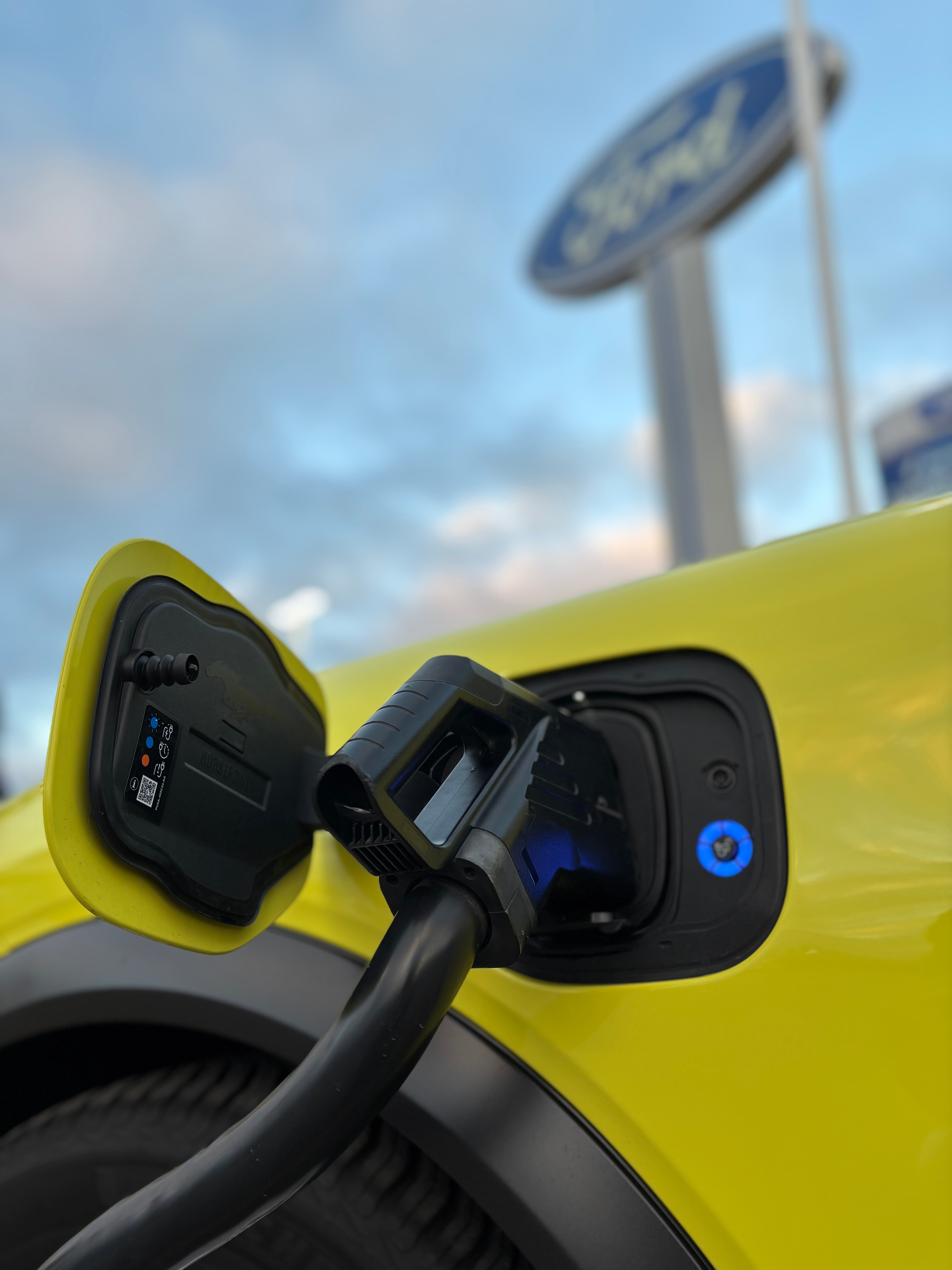 An electric vehicle charger plugged into a yellow vehicle.