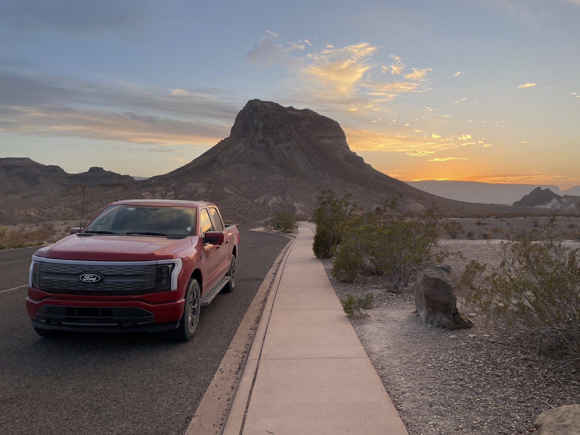 A red F-150 Lightning with a mountainous formation in the background.