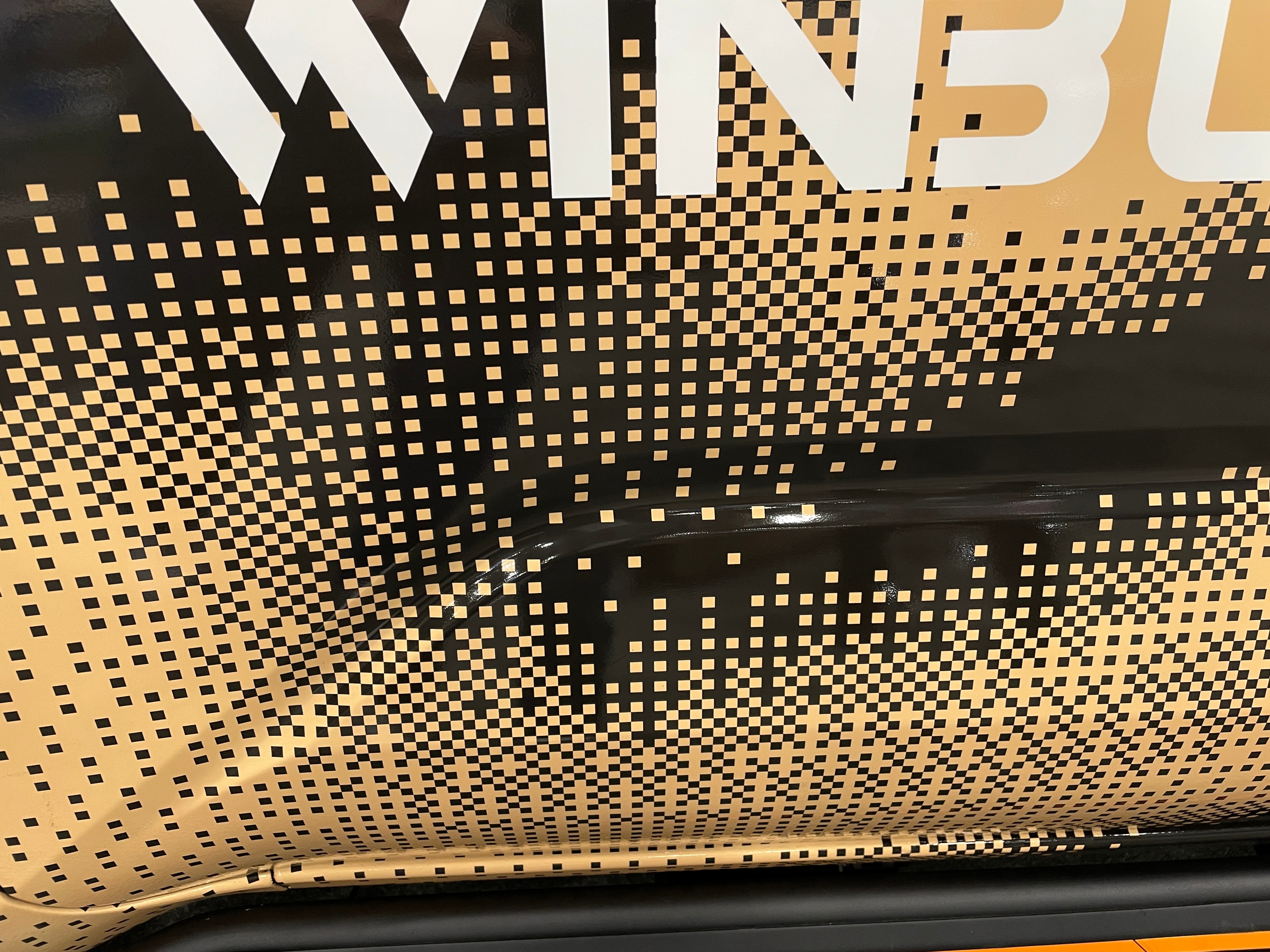 An up-close photo of a gold and black car wrap at a car show