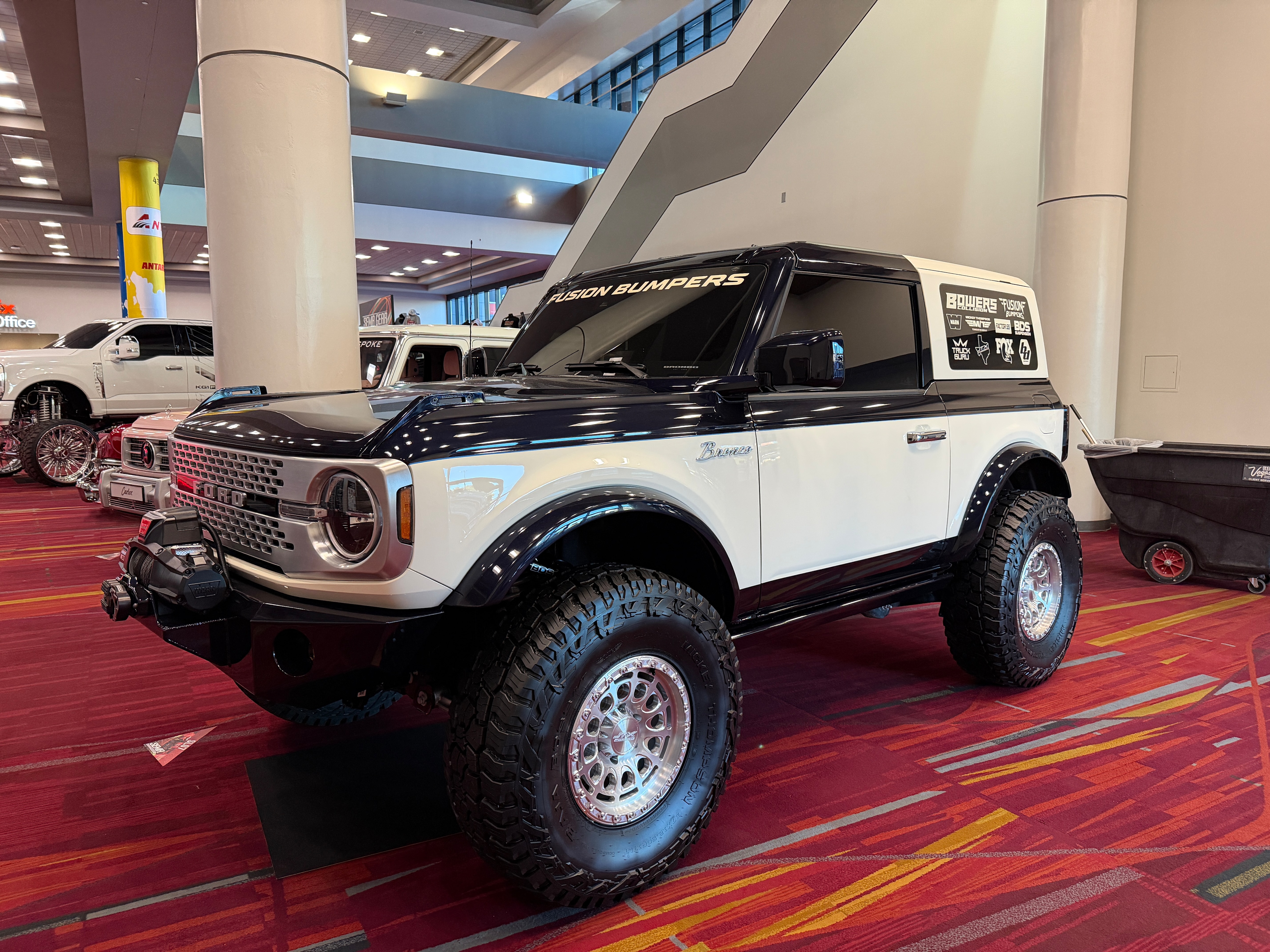 A vintage-looking black and white Bronco displayed at a car show