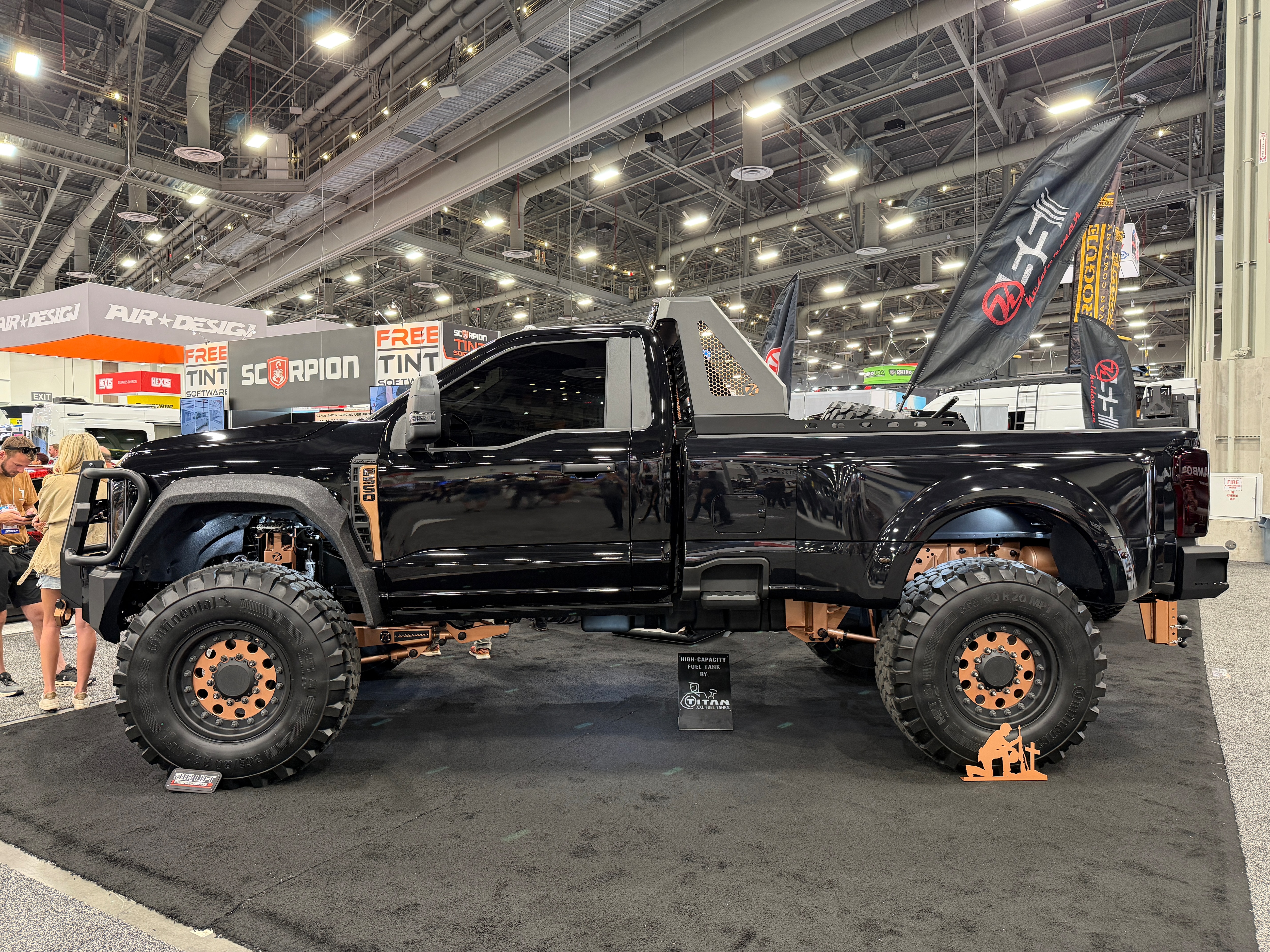 A large, modified black truck with orange accents at a car show