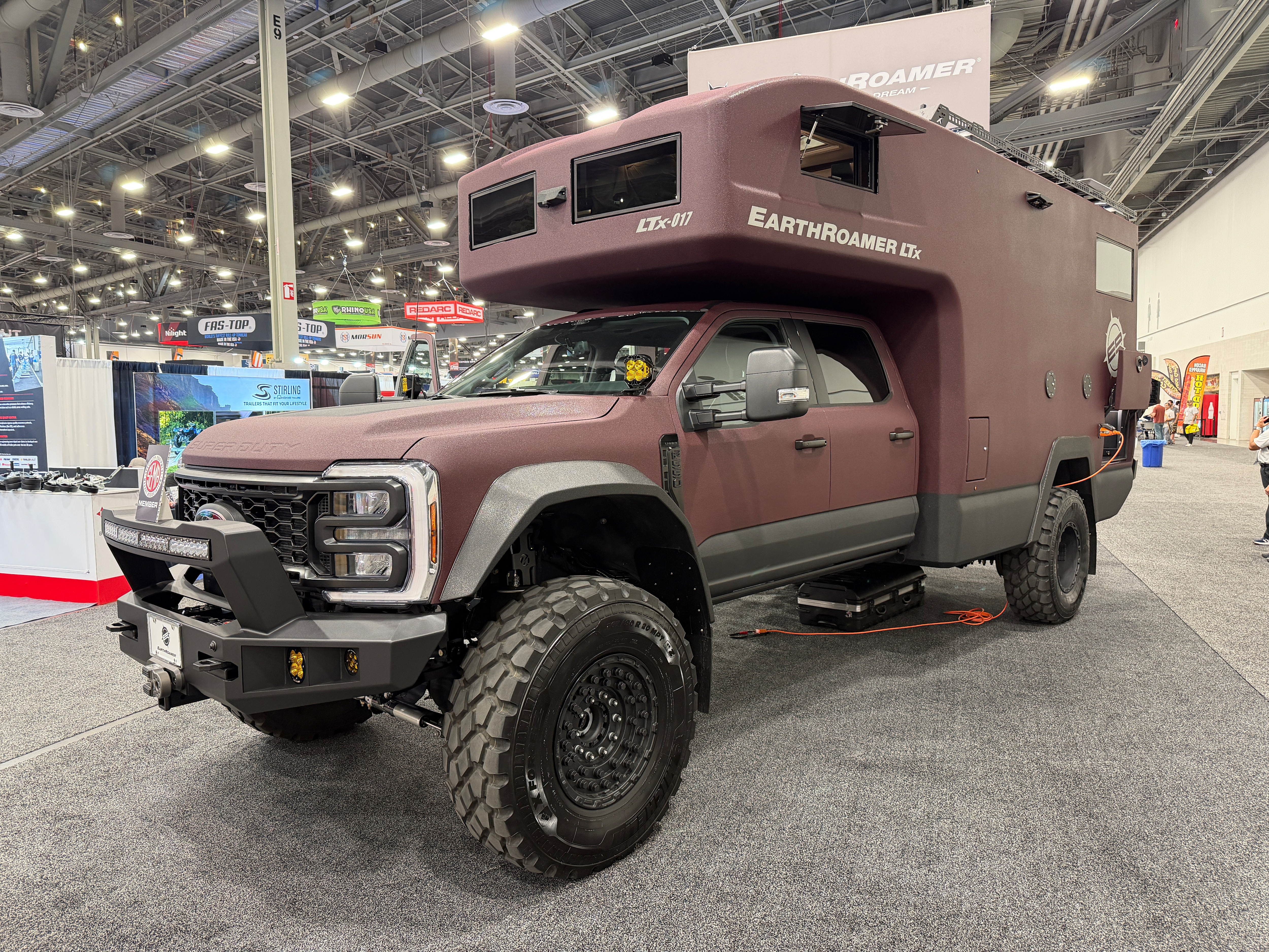 A large brown truck with a camper displayed at a car show