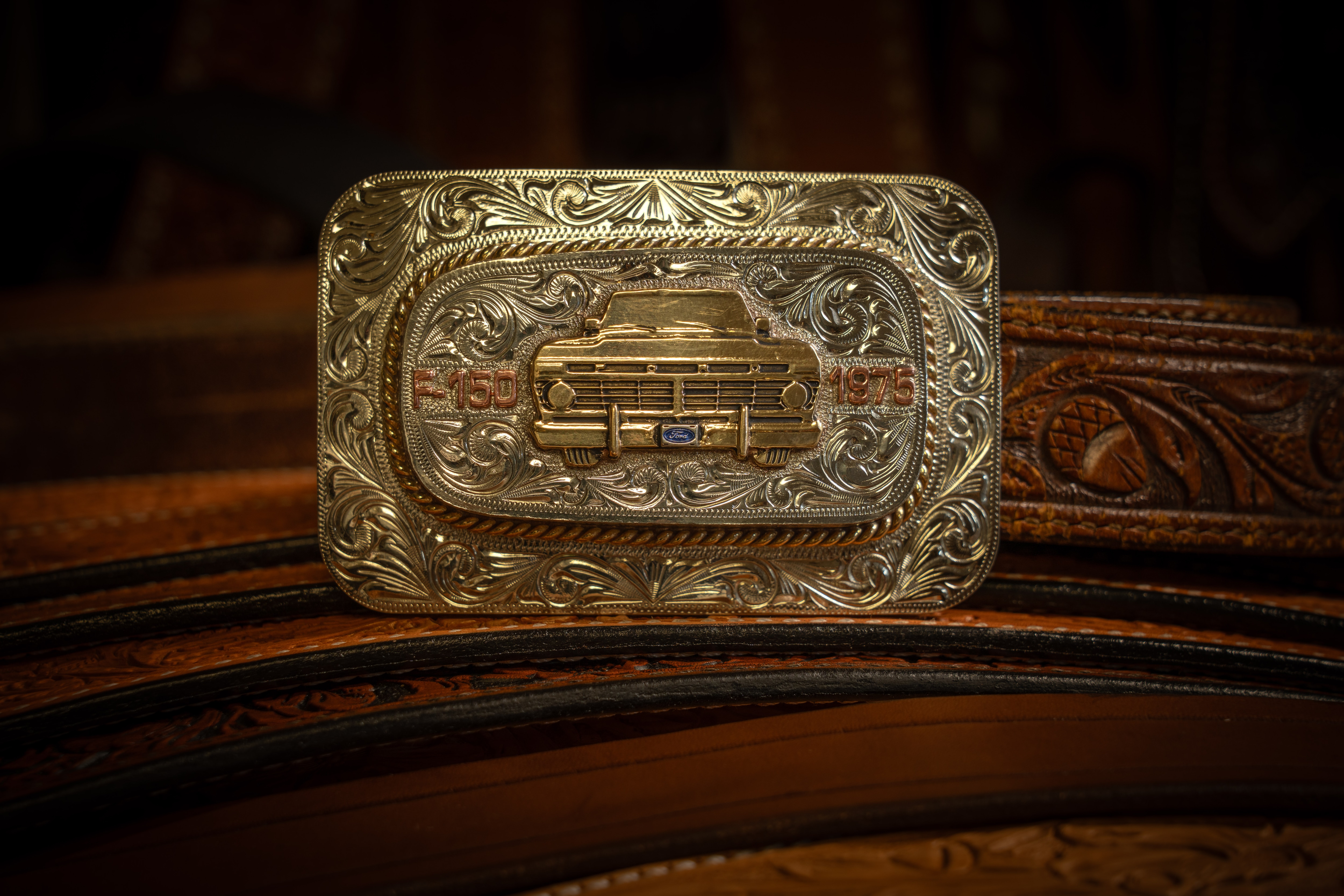 An ornate gold belt buckle with a truck on it