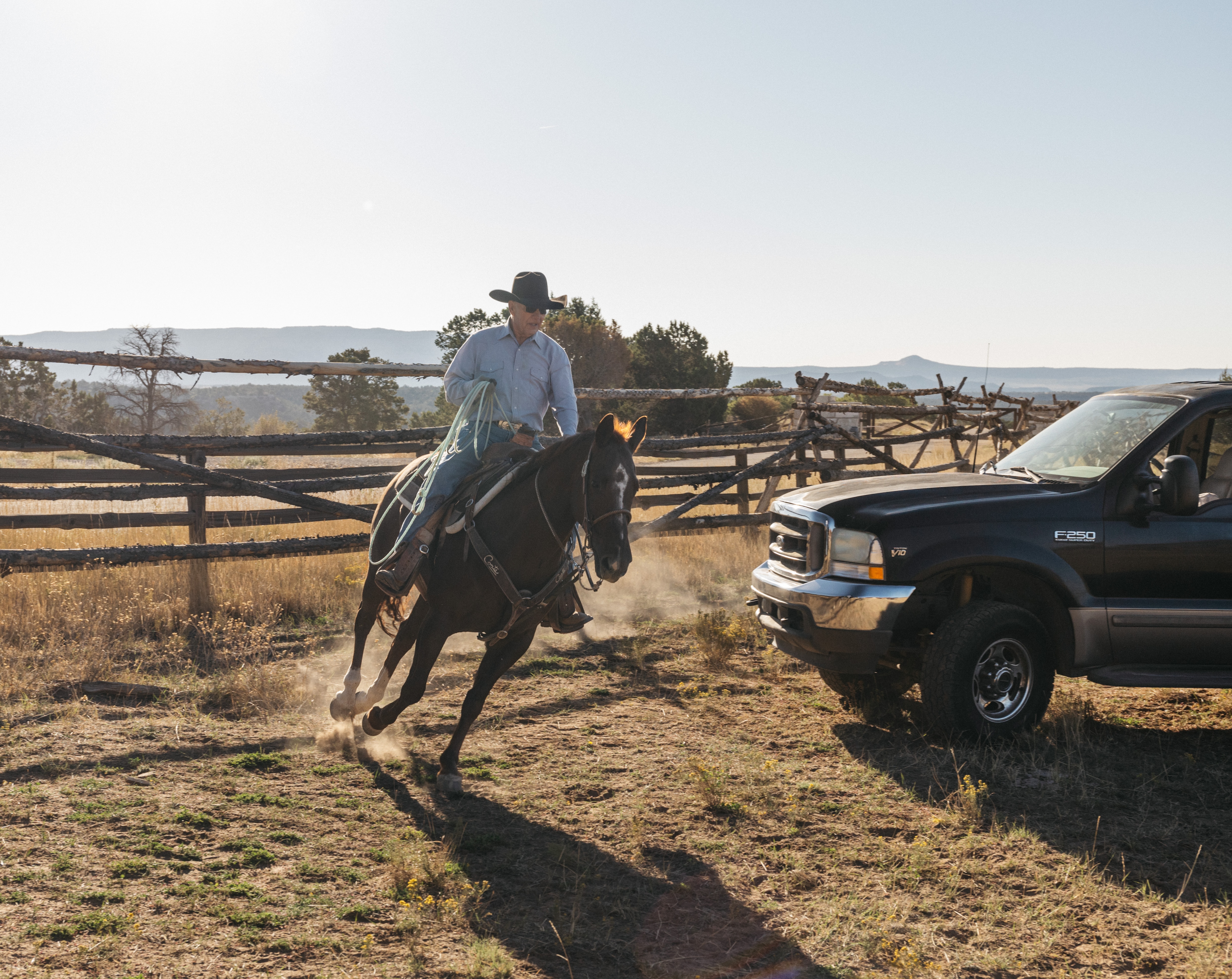 A man rides a horse near a black Ford F-250 truck.
