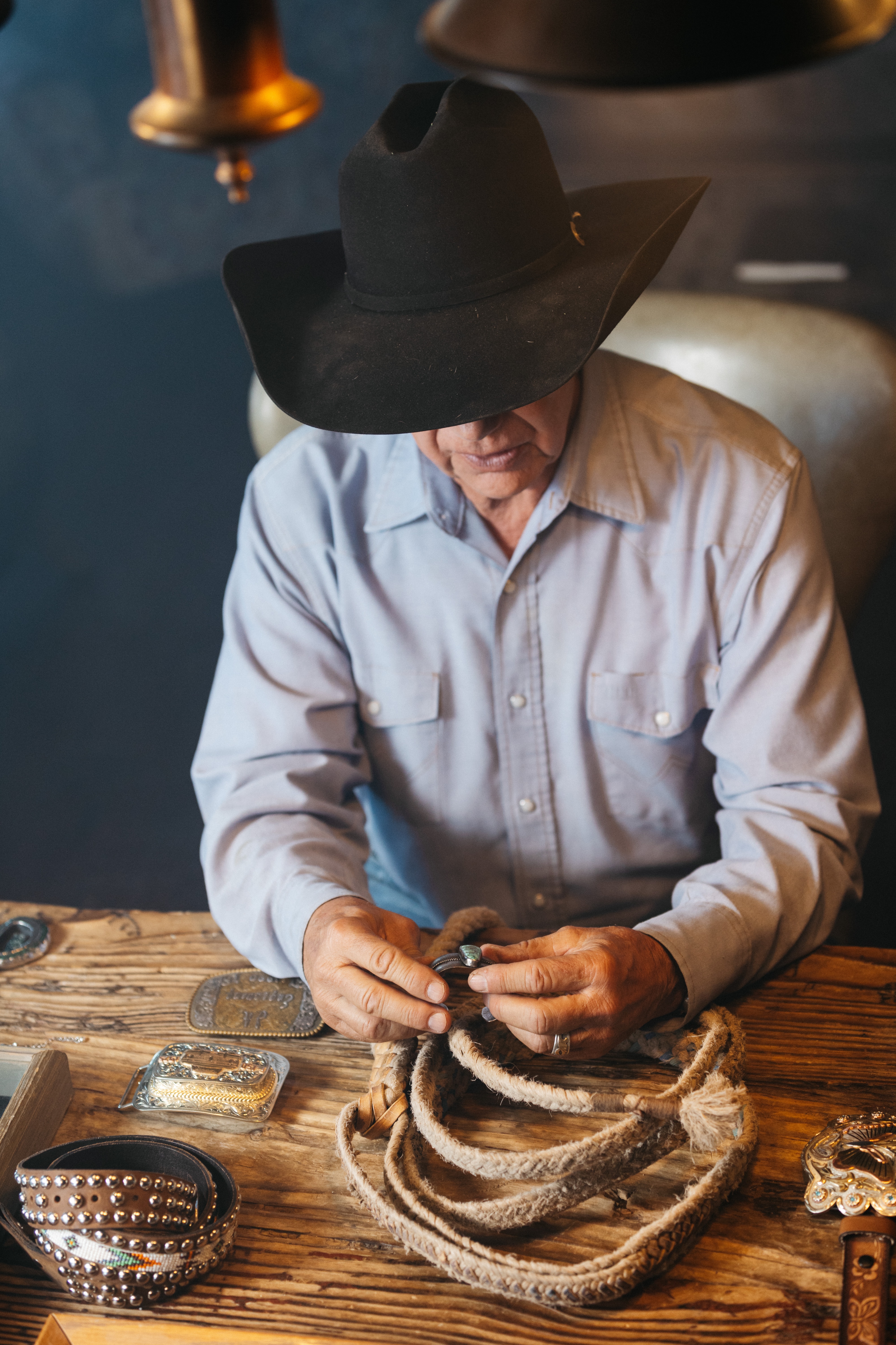 A man inspects a bracelet he crafted at his work station.