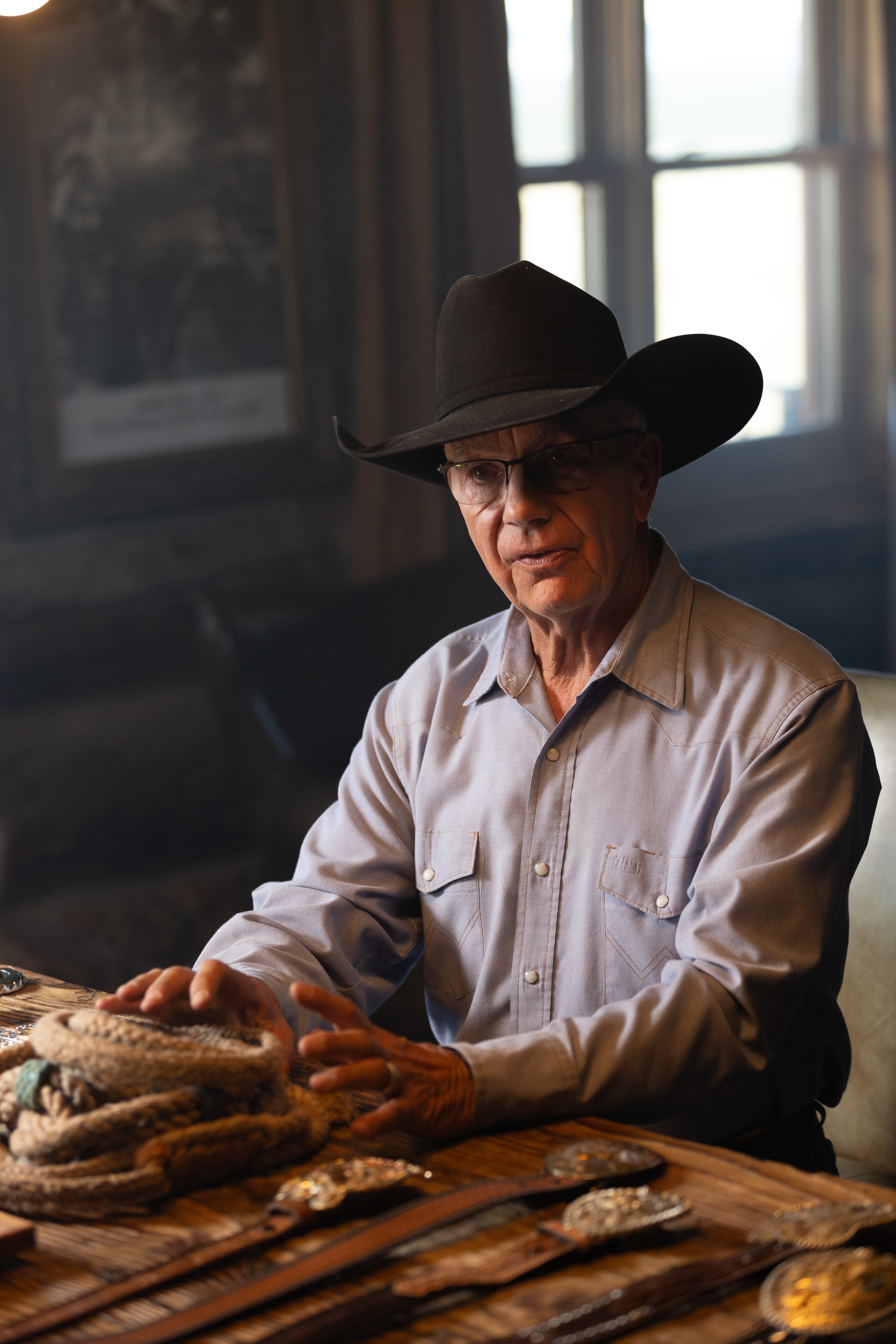 A man speaks at his desk where he makes belt buckles and other goods.