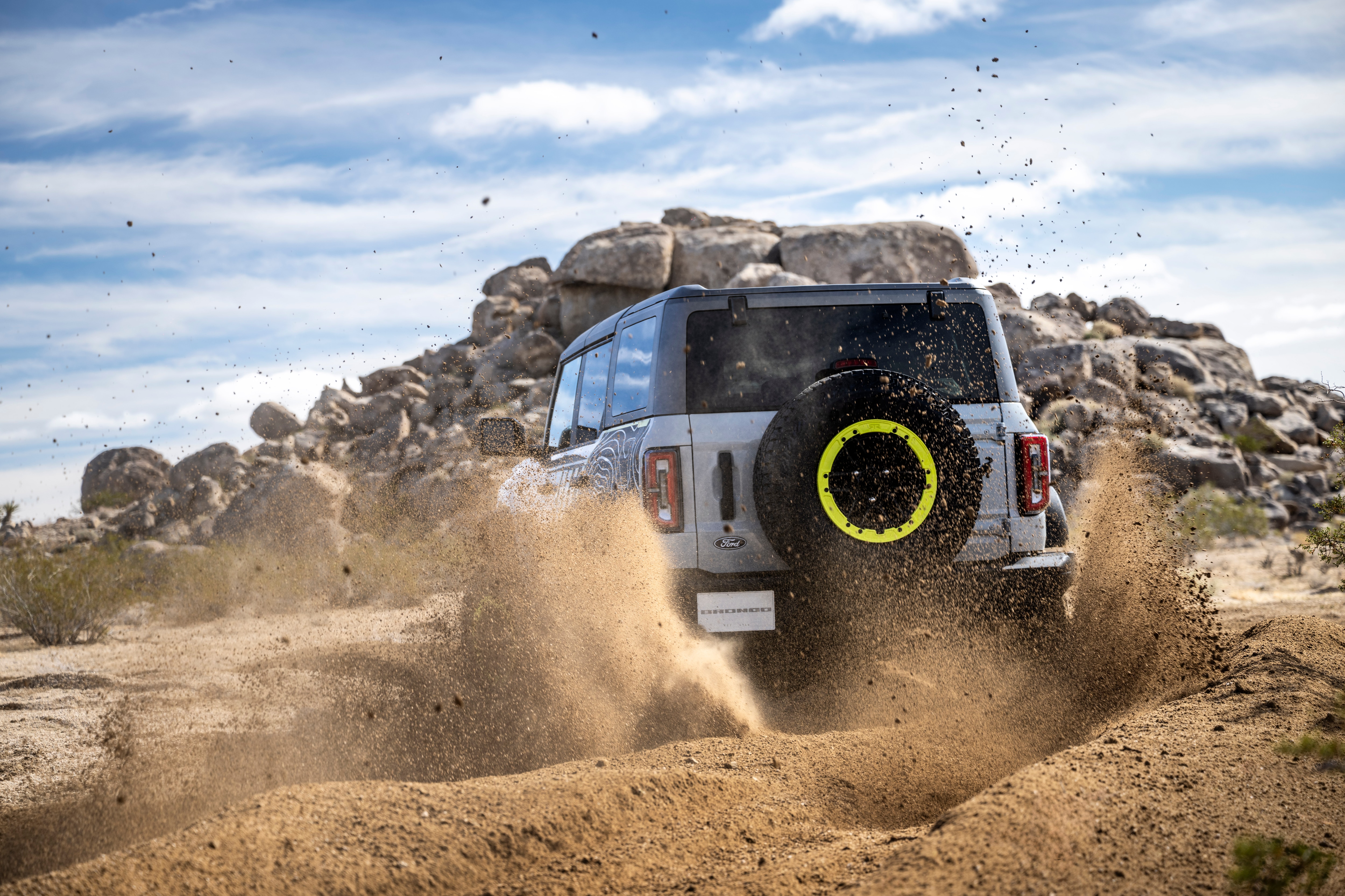 The back of the Bronco RTR, grey with lime green highlights, kicking up dirt