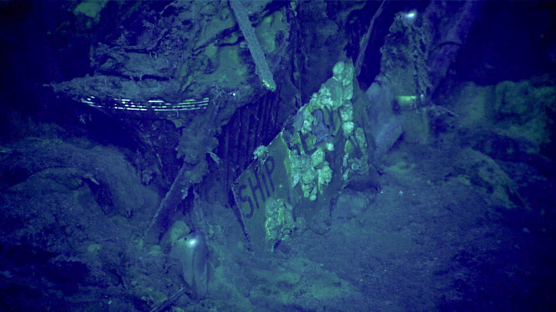 The front plate of the automobile discovered in the hangar of USS Yorktown during the seventh dive of the Papahānaumokuākea ROV and Mapping expedition on April 20. The top line reads “SHIP SERVICE;” the bottom line is more obscured, but could read “CV-5 NAVY” or “US NAVY.” Image courtesy of NOAA Ocean Exploration, 2025 Beyond the Blue.