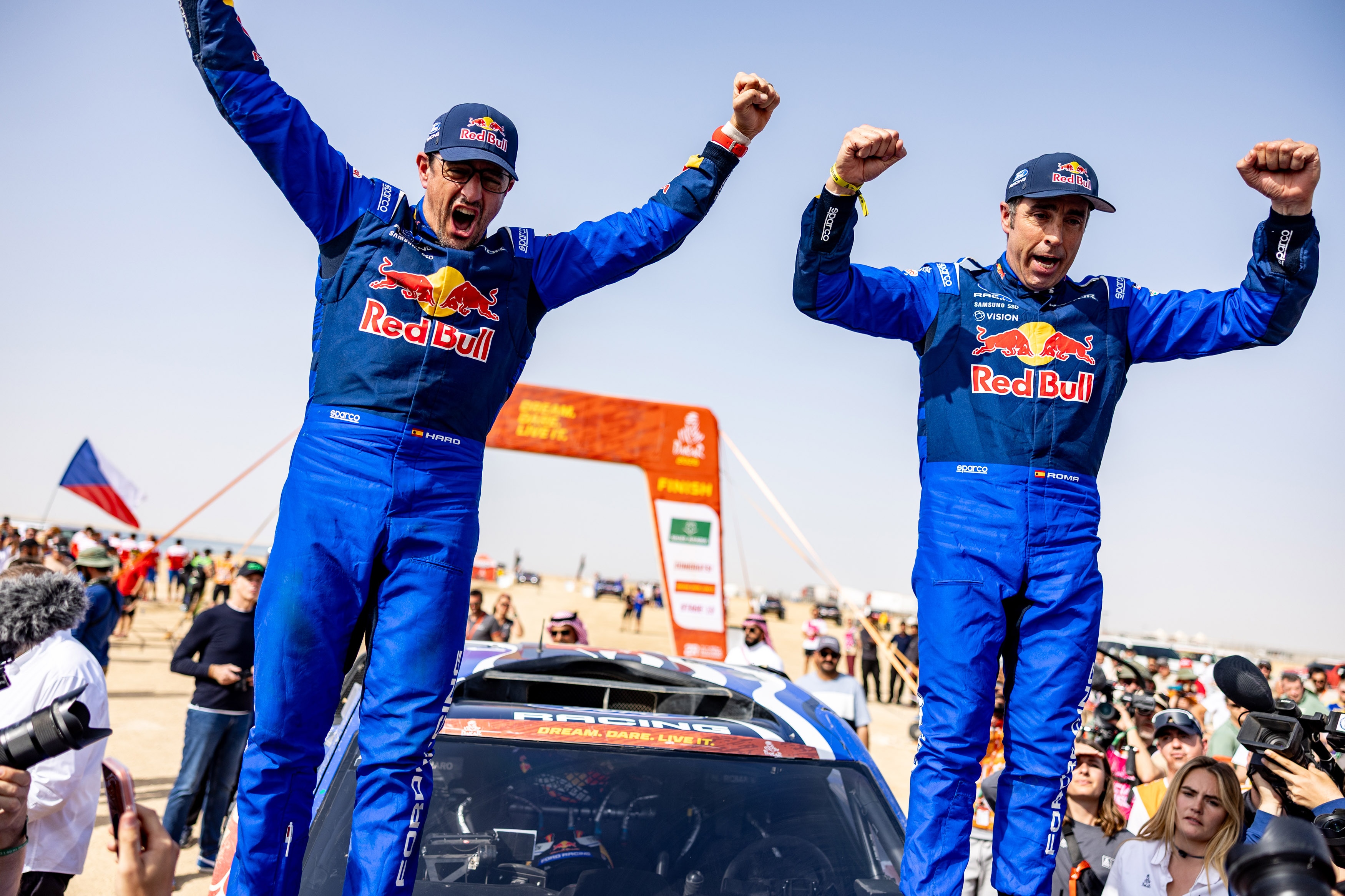 Two men in Ford Red Bull racing uniforms cheer.