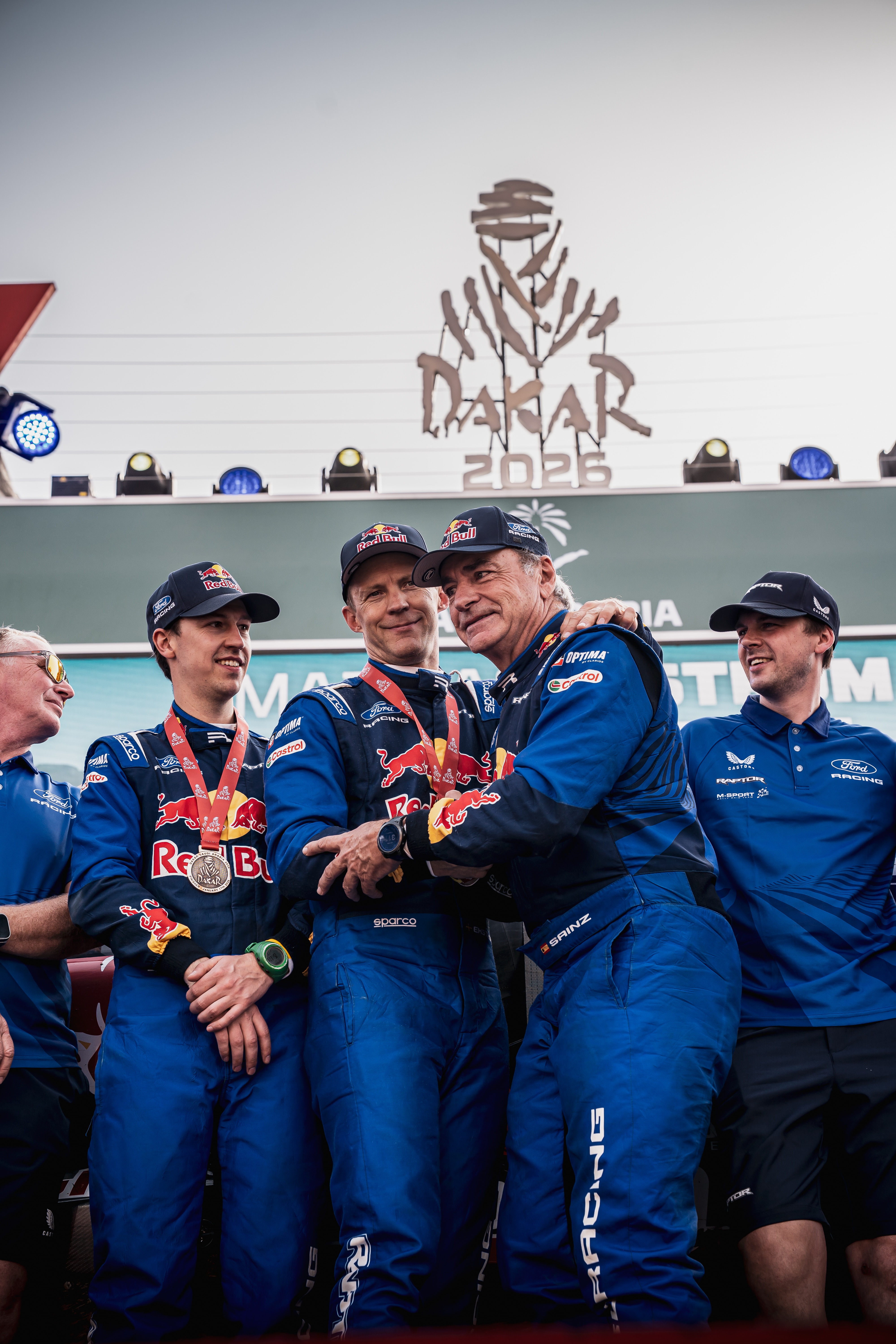 A group of men in blue Ford Racing uniforms beneath a Dakar 2026 sign. 