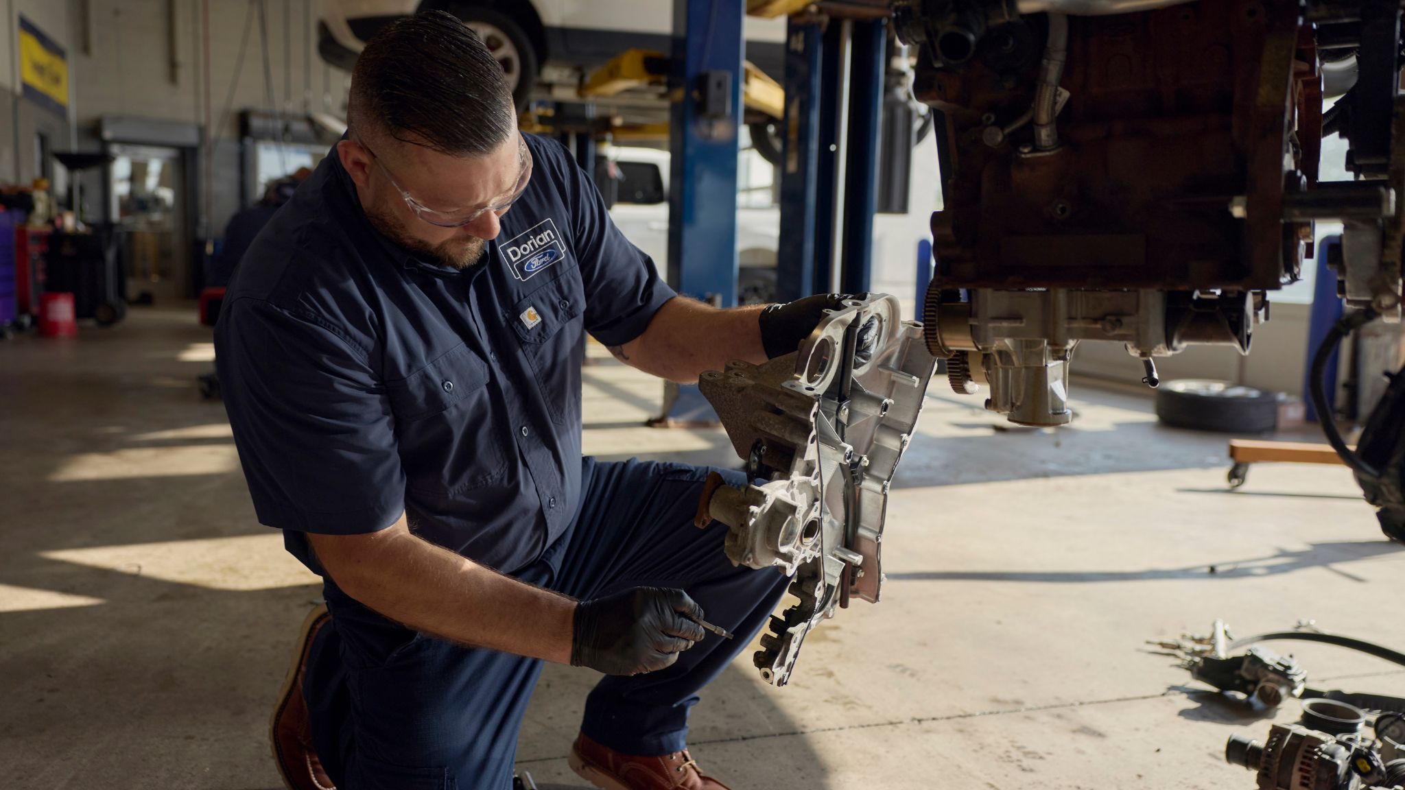 A man in a blue jumpsuit works on a vehicle.