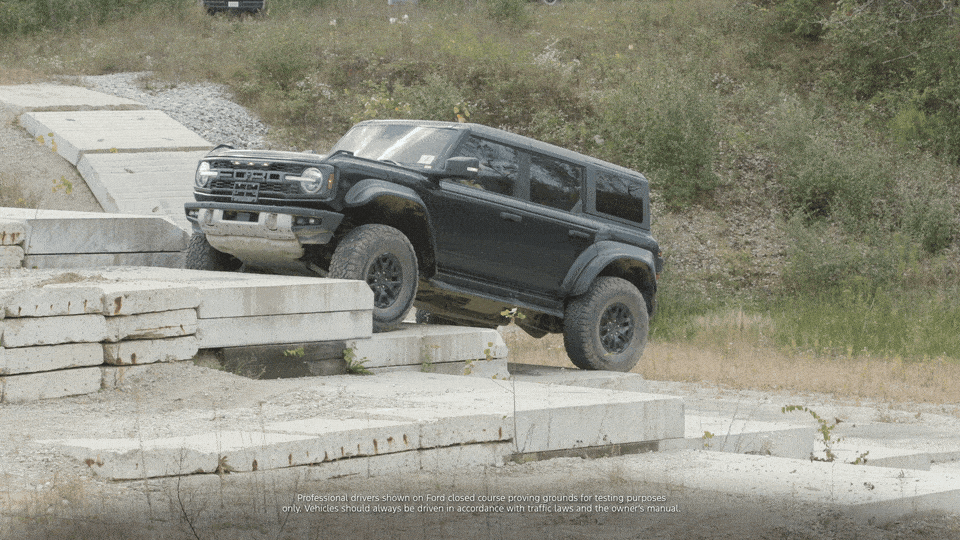 A black Ford Bronco climbs an incline of stair-like concrete blocks at the Michigan Proving Grounds.