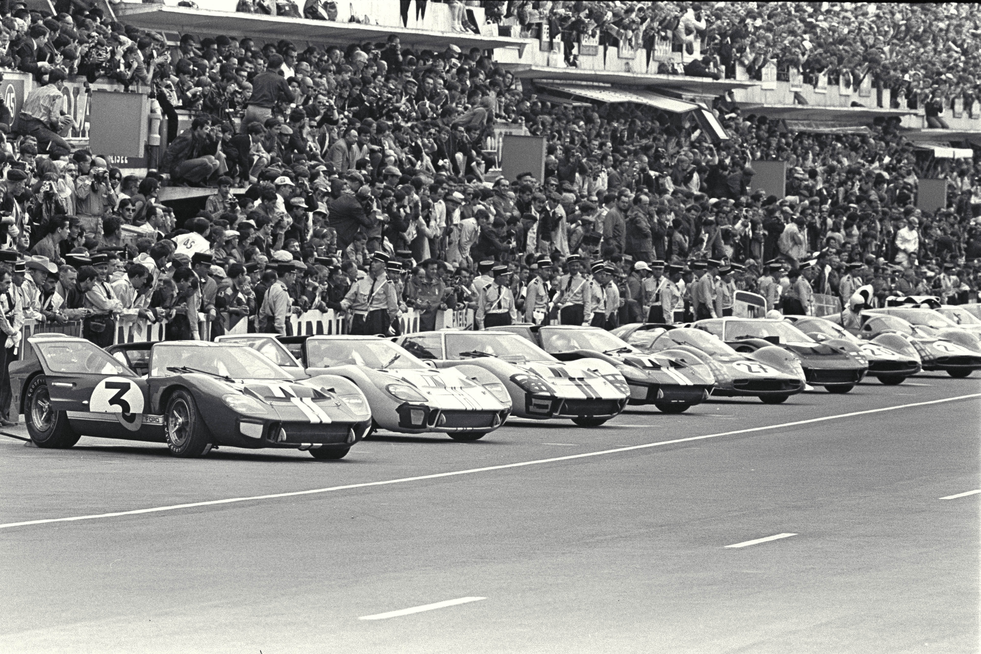 A black and white photo of vehicles lined up on a racetrack in 1966.