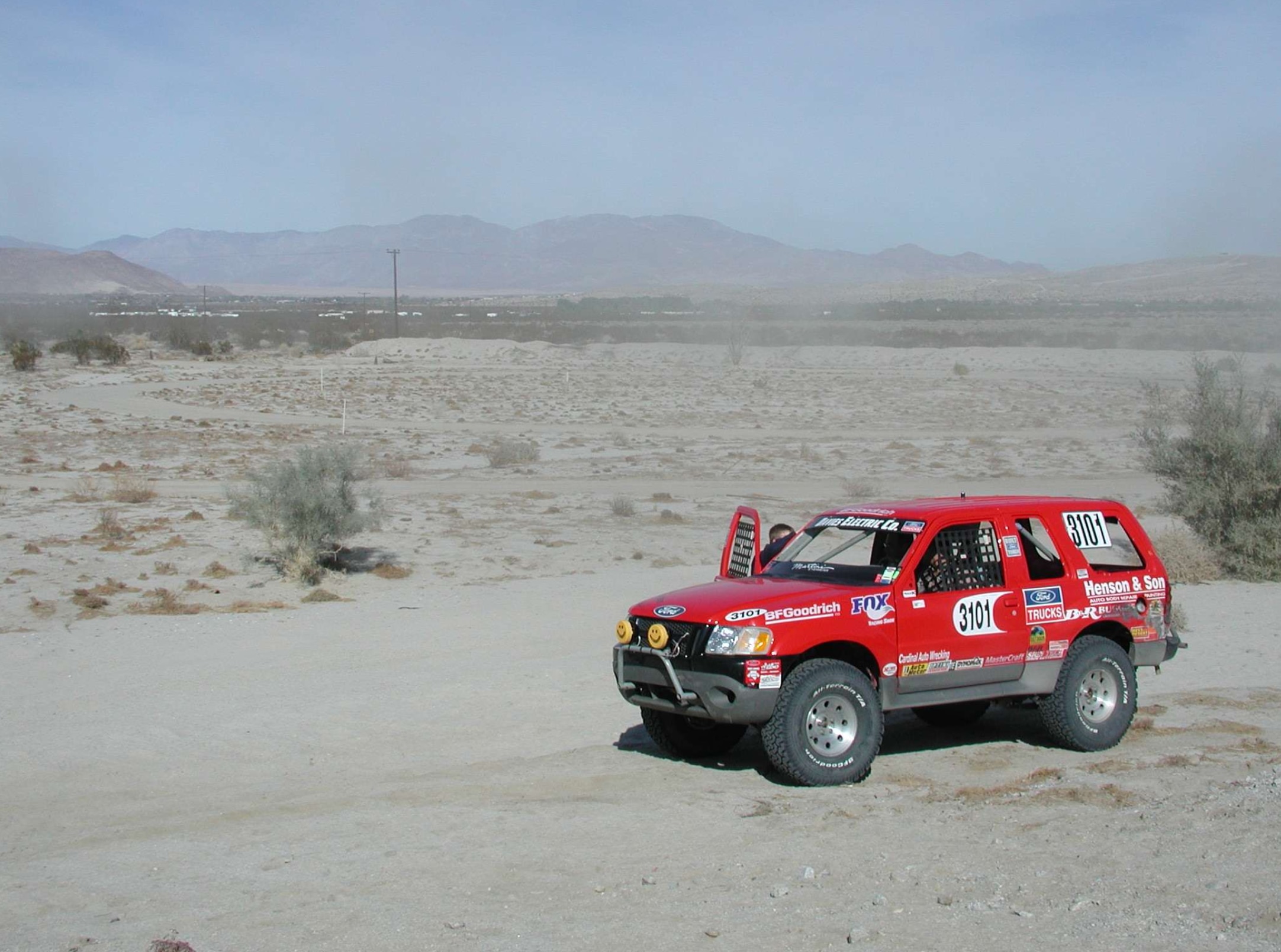 A development test vehicle kicks up sand as it navigates rigorous desert durability runs.