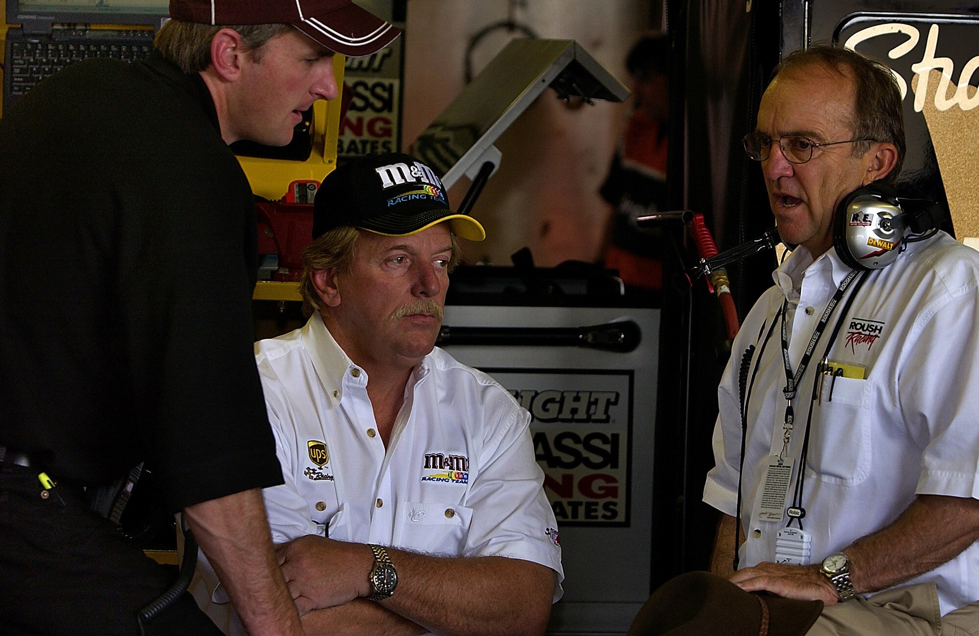Three men talking at a NASCAR event.