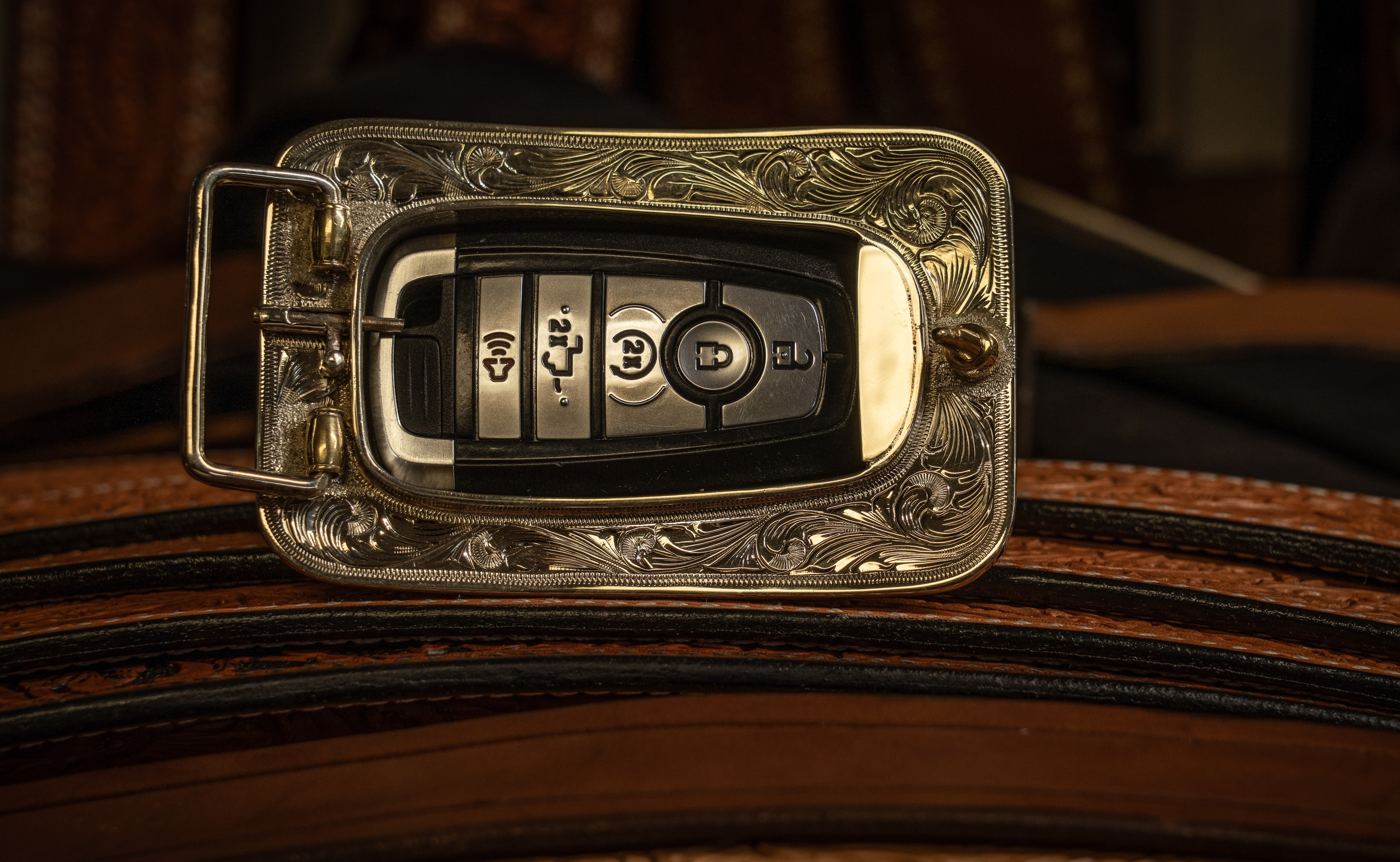The back of a gold belt buckle is shown holding a key fob.